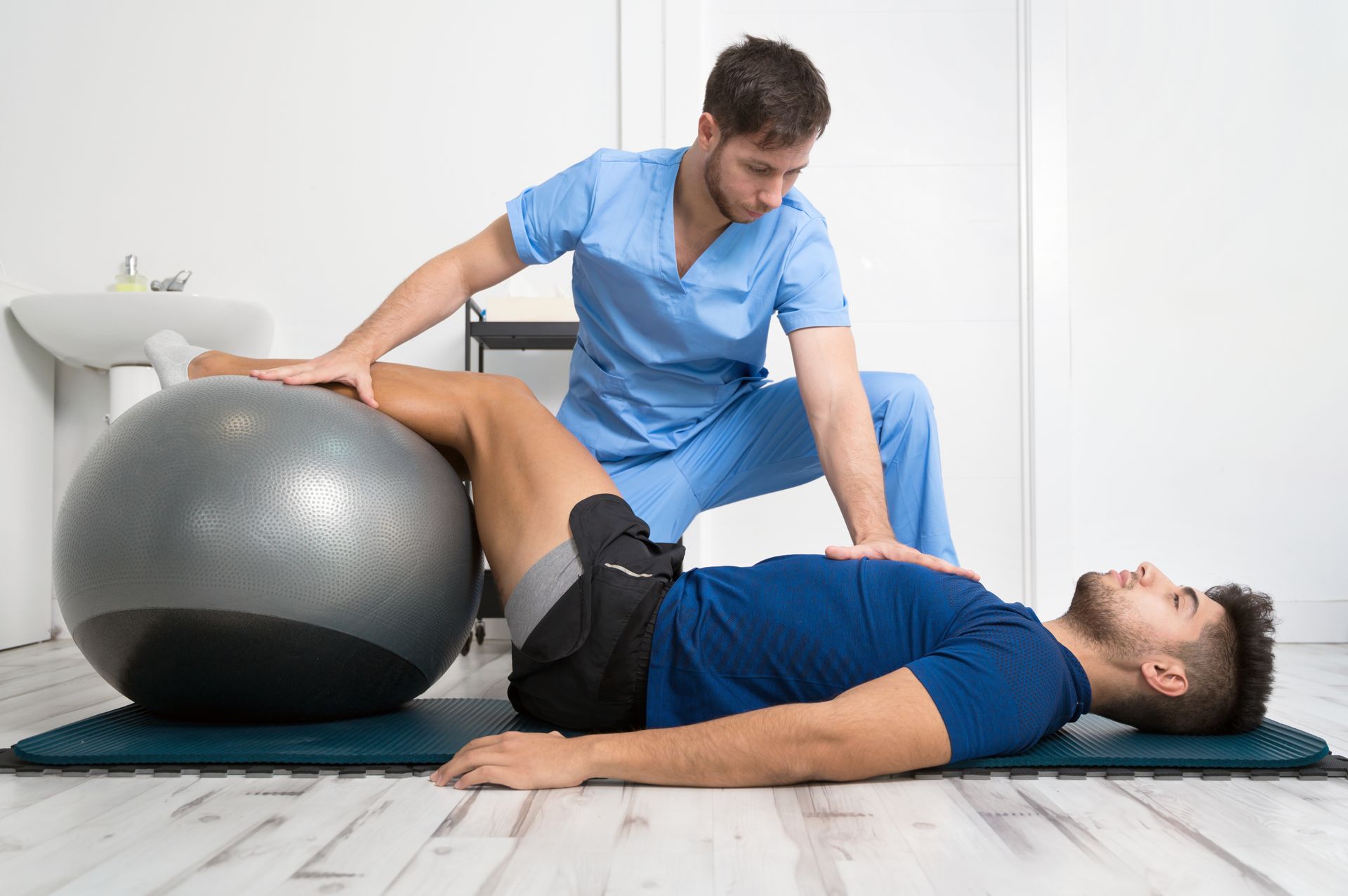 a man is laying on the floor with a pilates ball .
