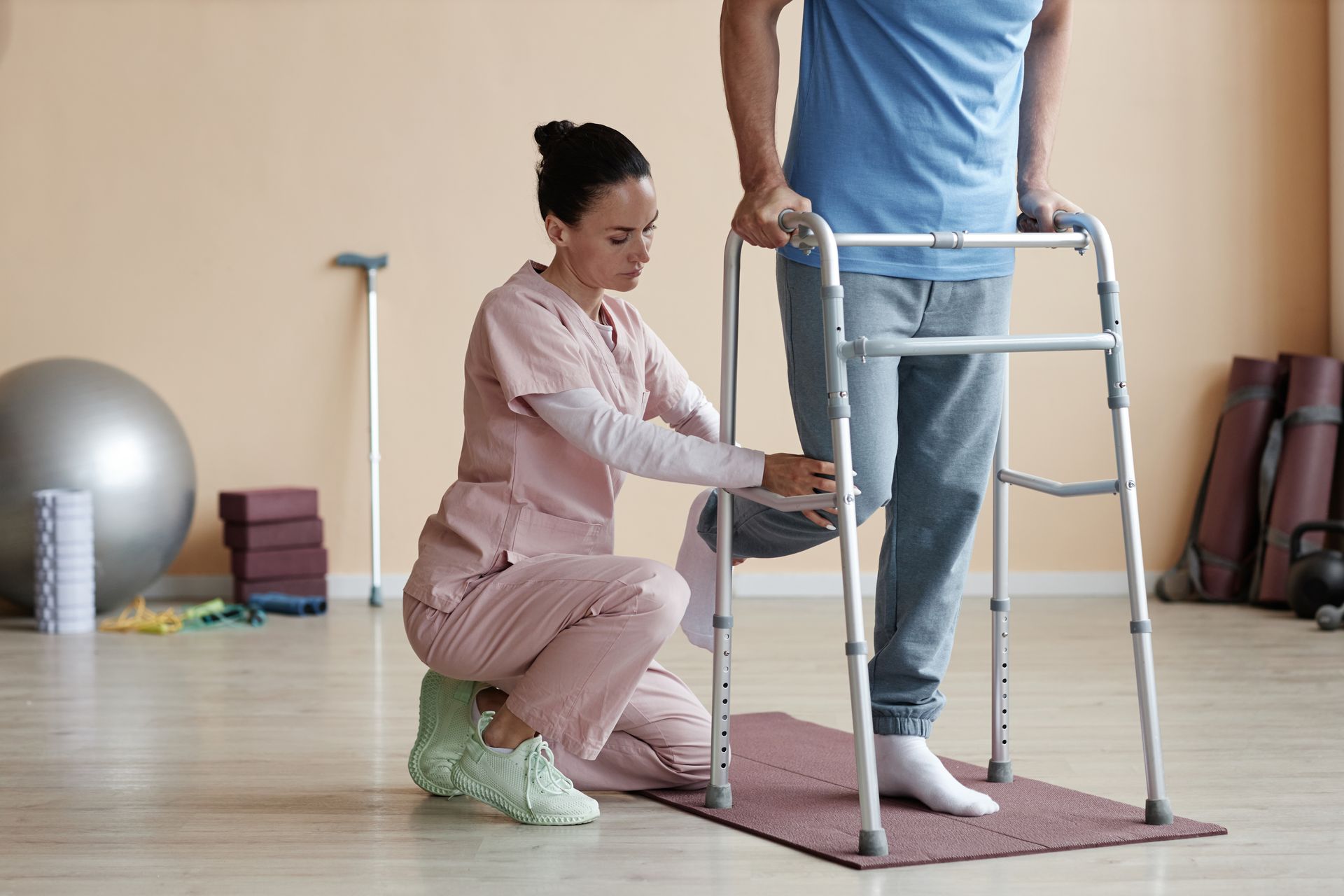 a woman is helping a man use a walker in a gym .