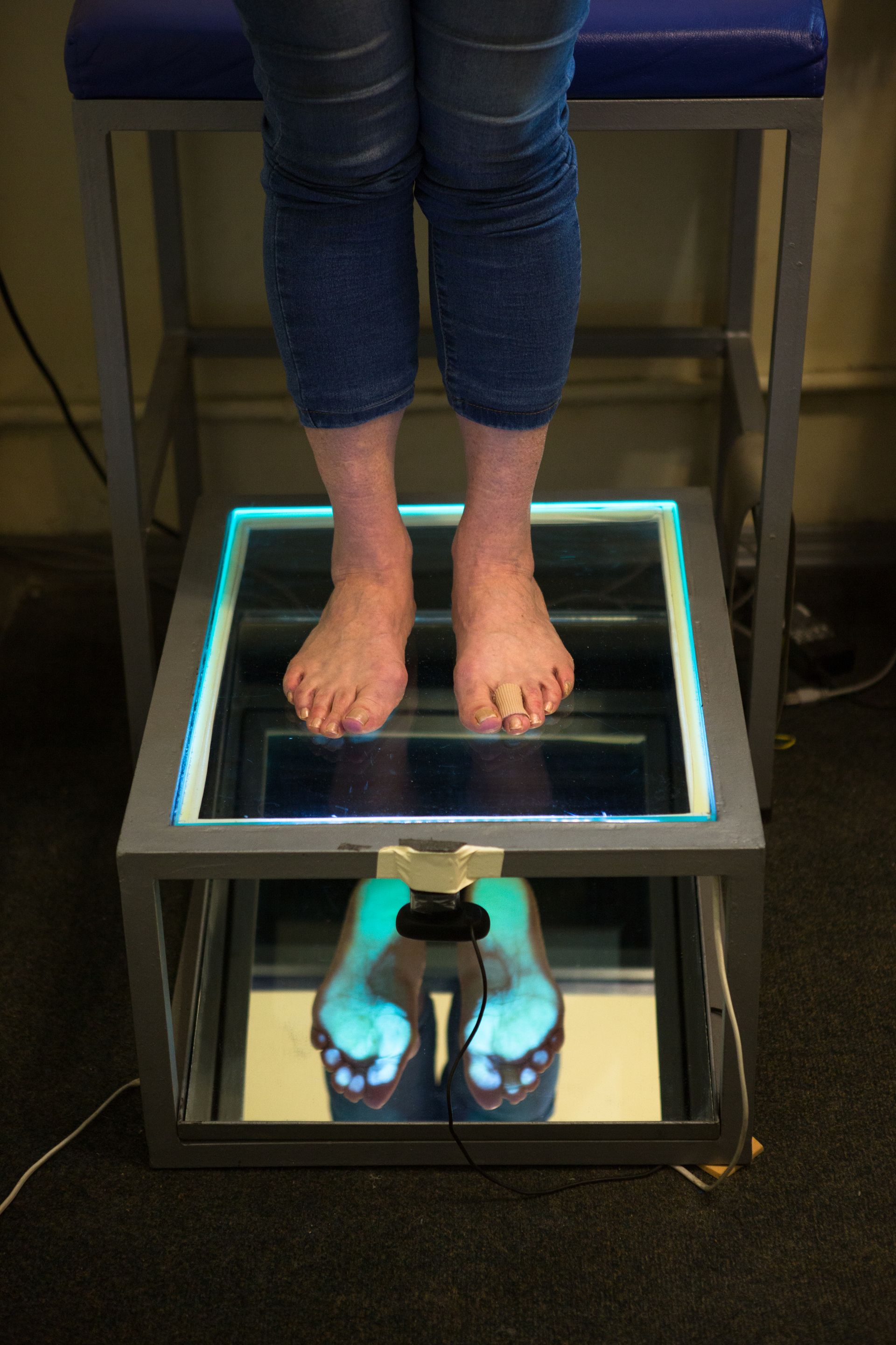 A person is sitting on a stool with their feet on a mirror.