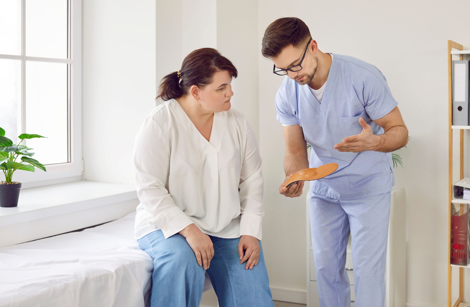 A doctor is talking to a patient who is sitting on a bed.