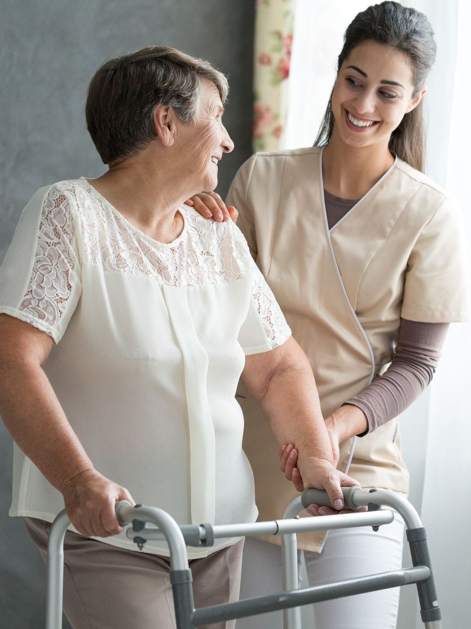 a nurse is helping an elderly woman with a walker .