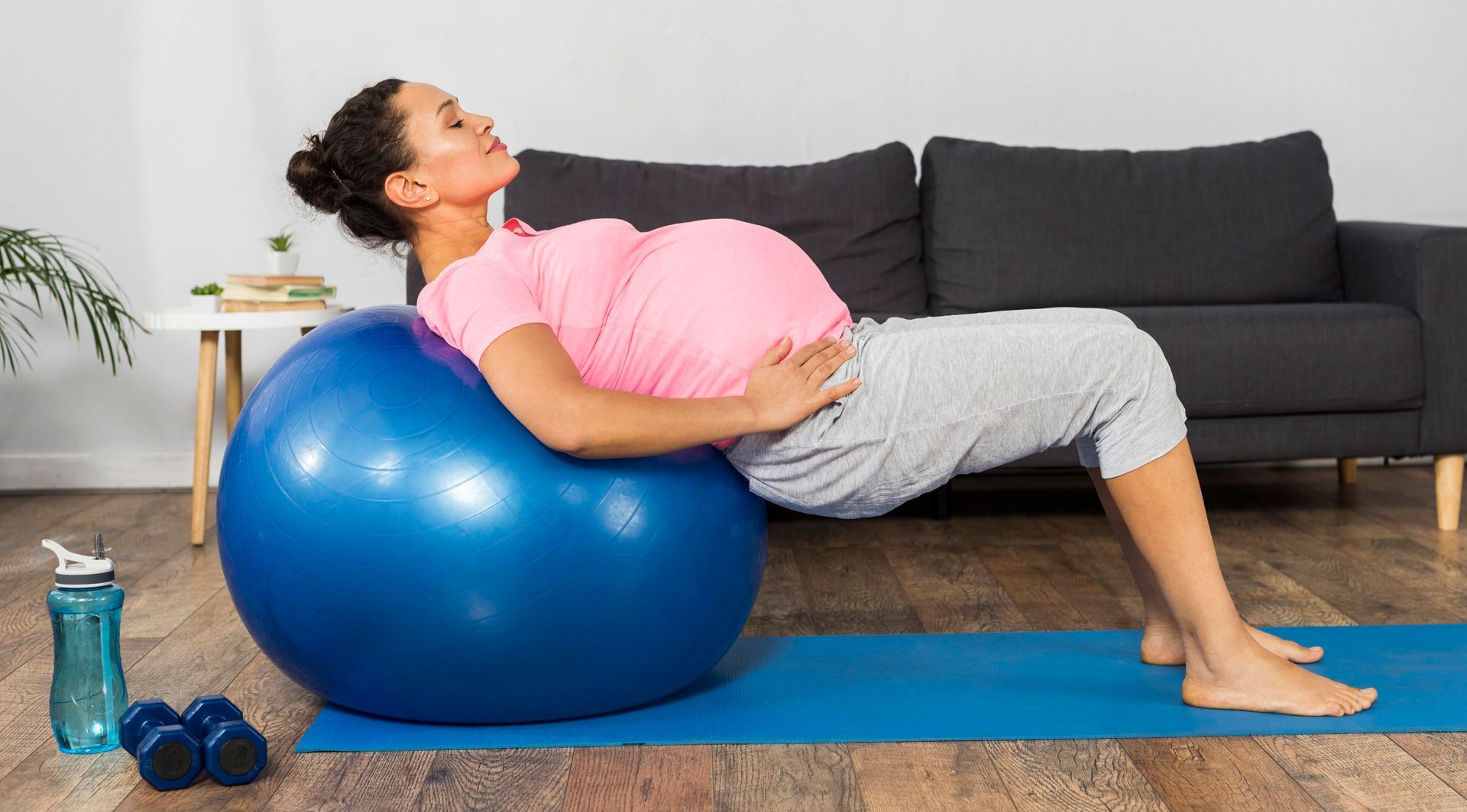 a pregnant woman is sitting on an exercise ball on a yoga mat .