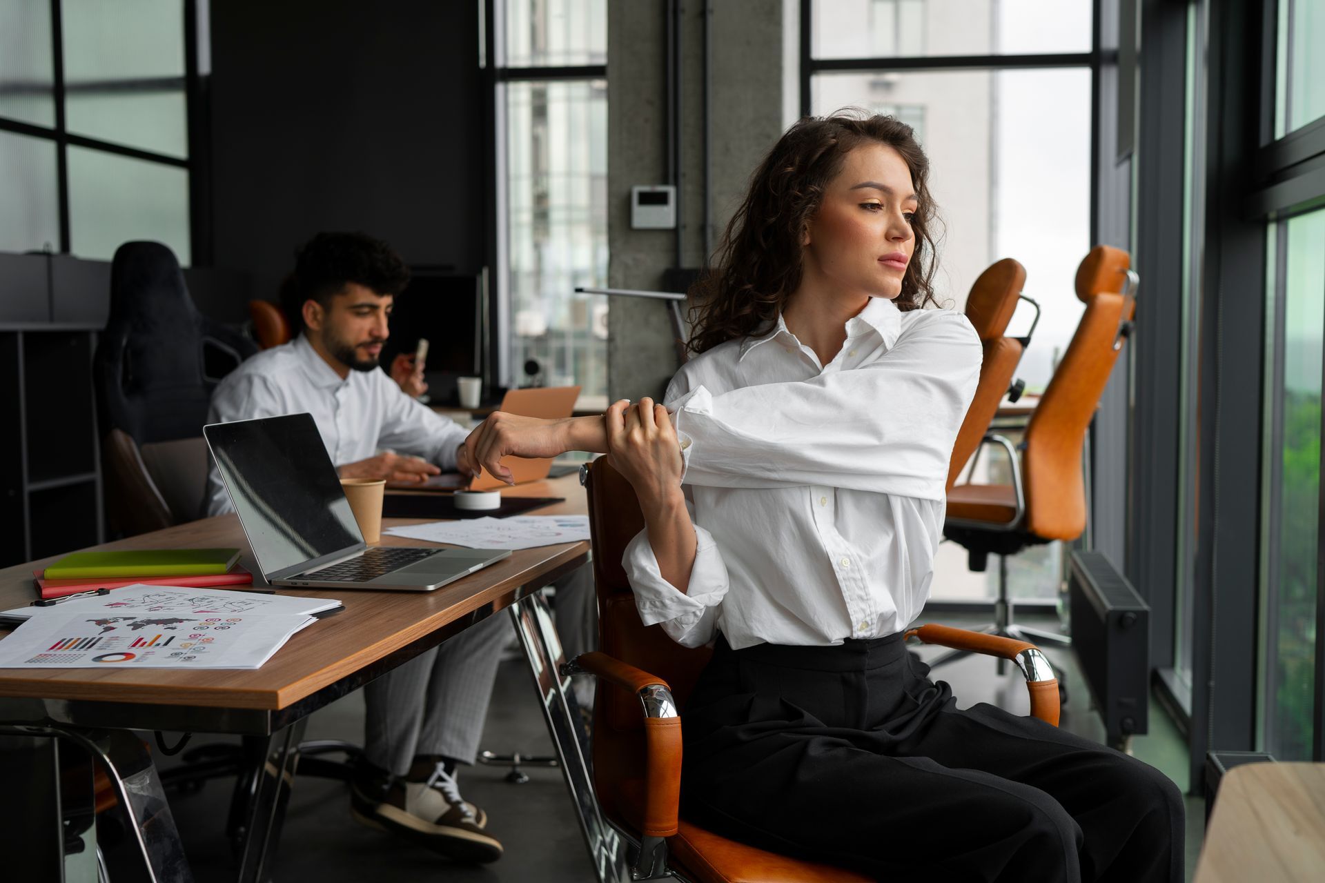 a woman is stretching her arms while sitting in an office chair .