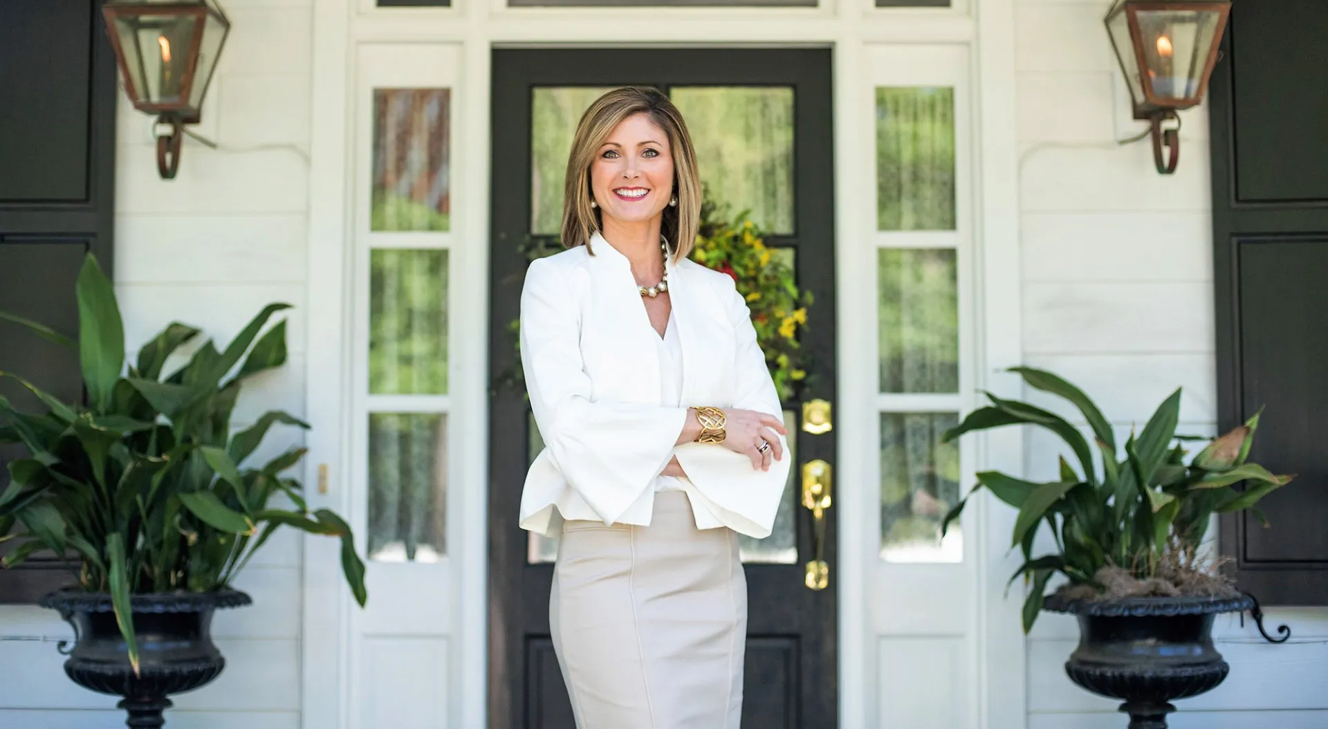 A woman is standing in front of a house with her arms crossed.