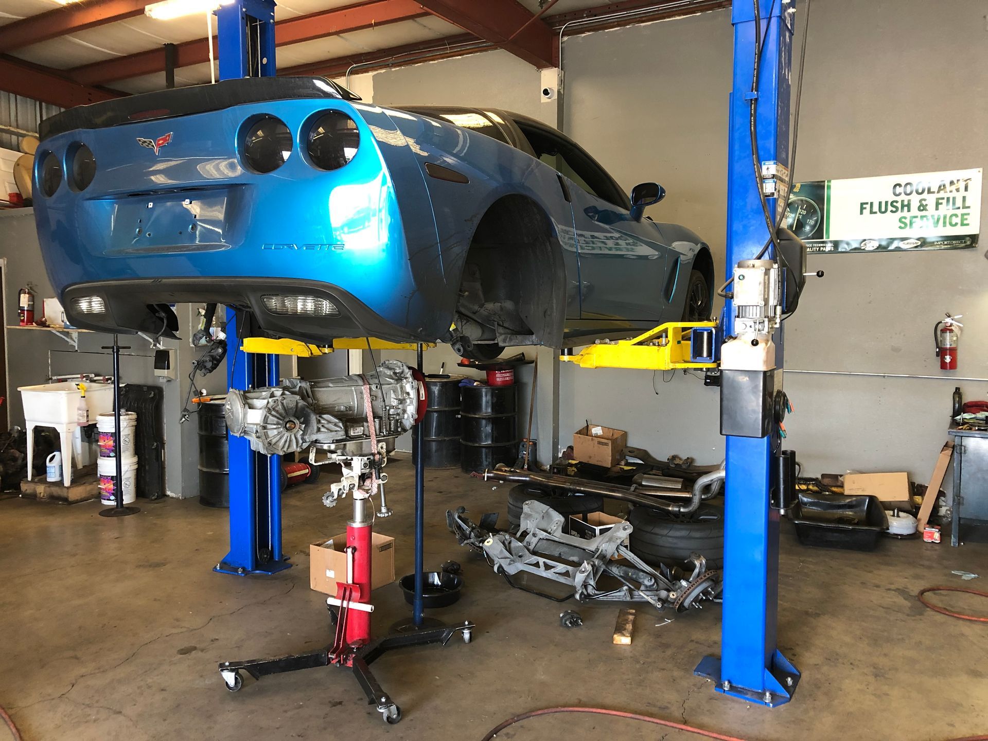 A blue car is sitting on a lift in a garage.