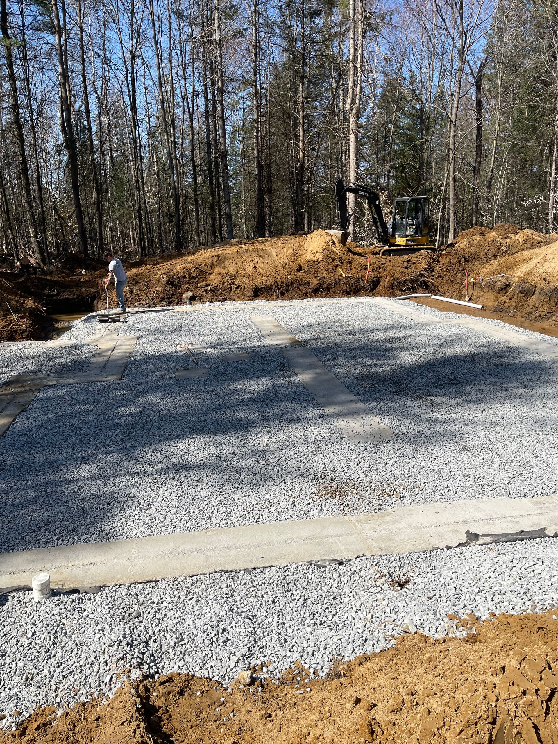 Un chantier de construction avec du gravier et de la terre et un bulldozer en arrière-plan.