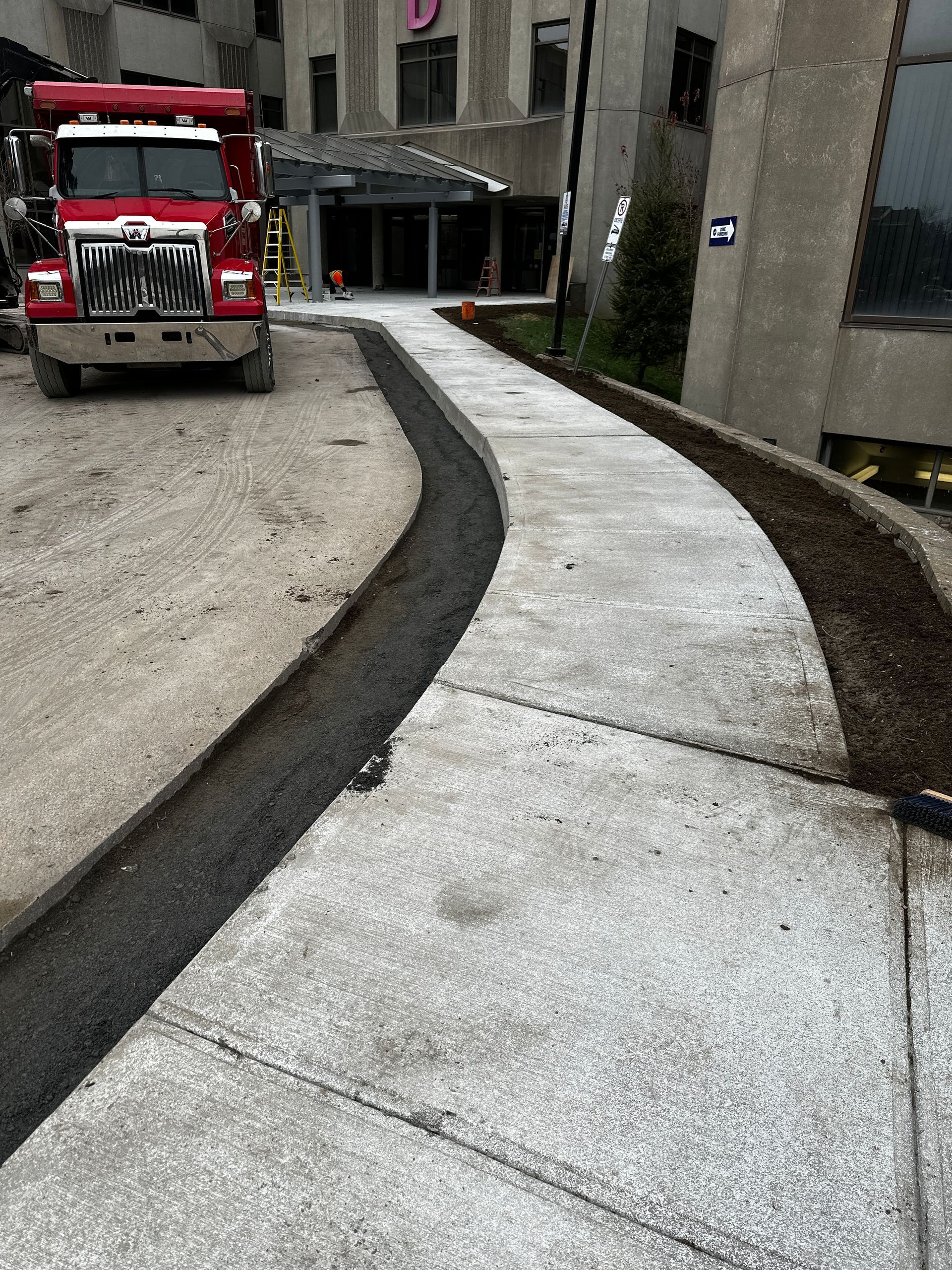 Un camion rouge est garé sur un trottoir à côté d’un immeuble.