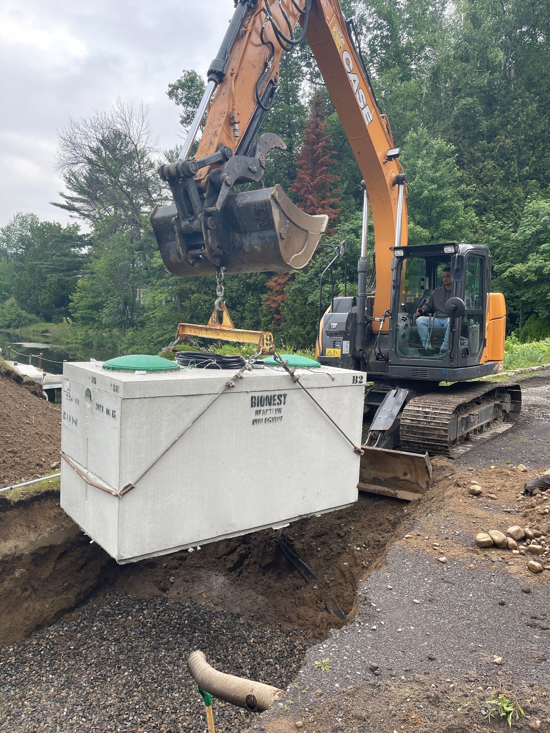 Une grosse excavatrice soulève une grande boîte blanche du sol.