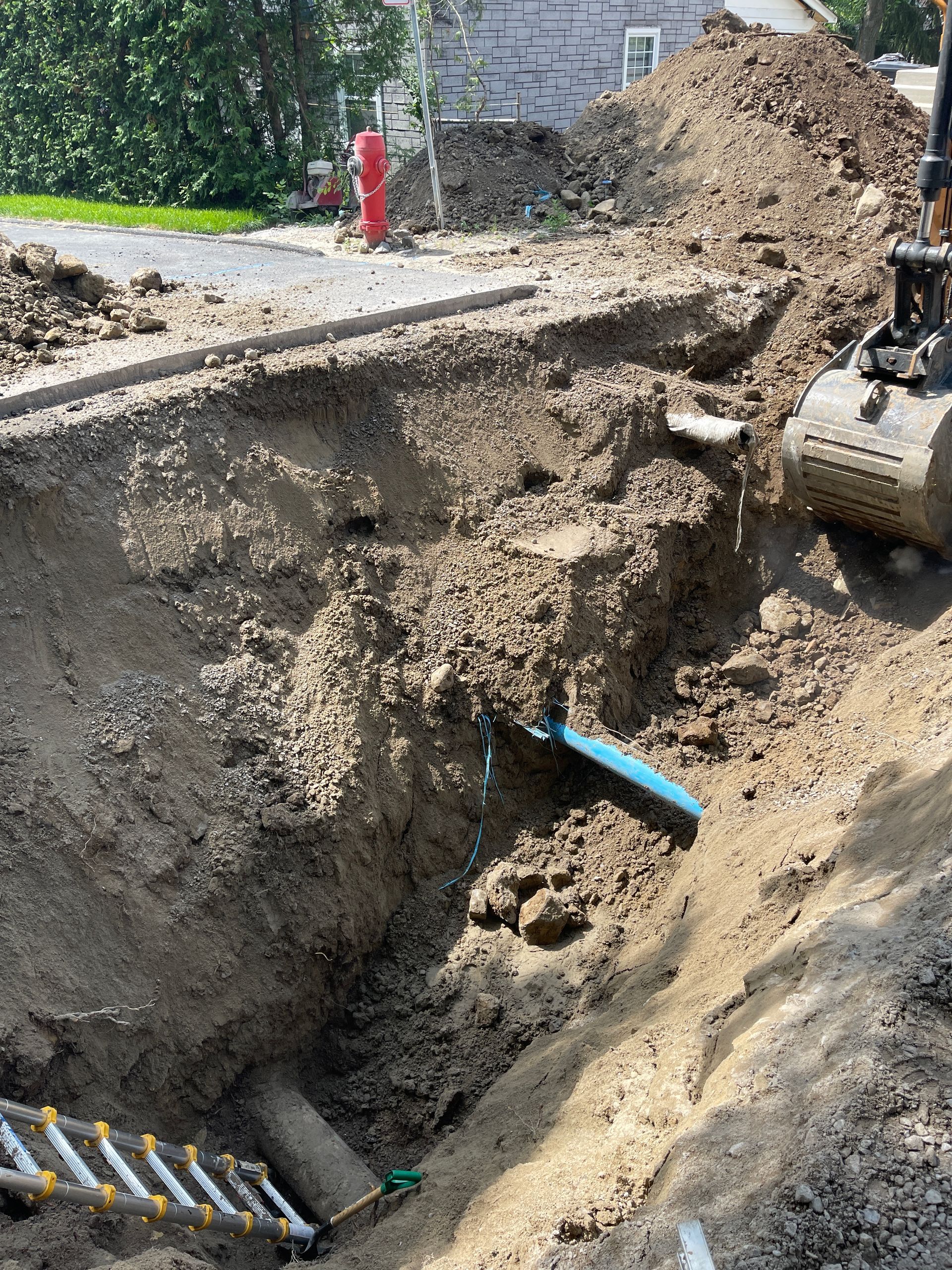 Un bulldozer creuse un trou dans le sol à côté d’une bouche d’incendie.
