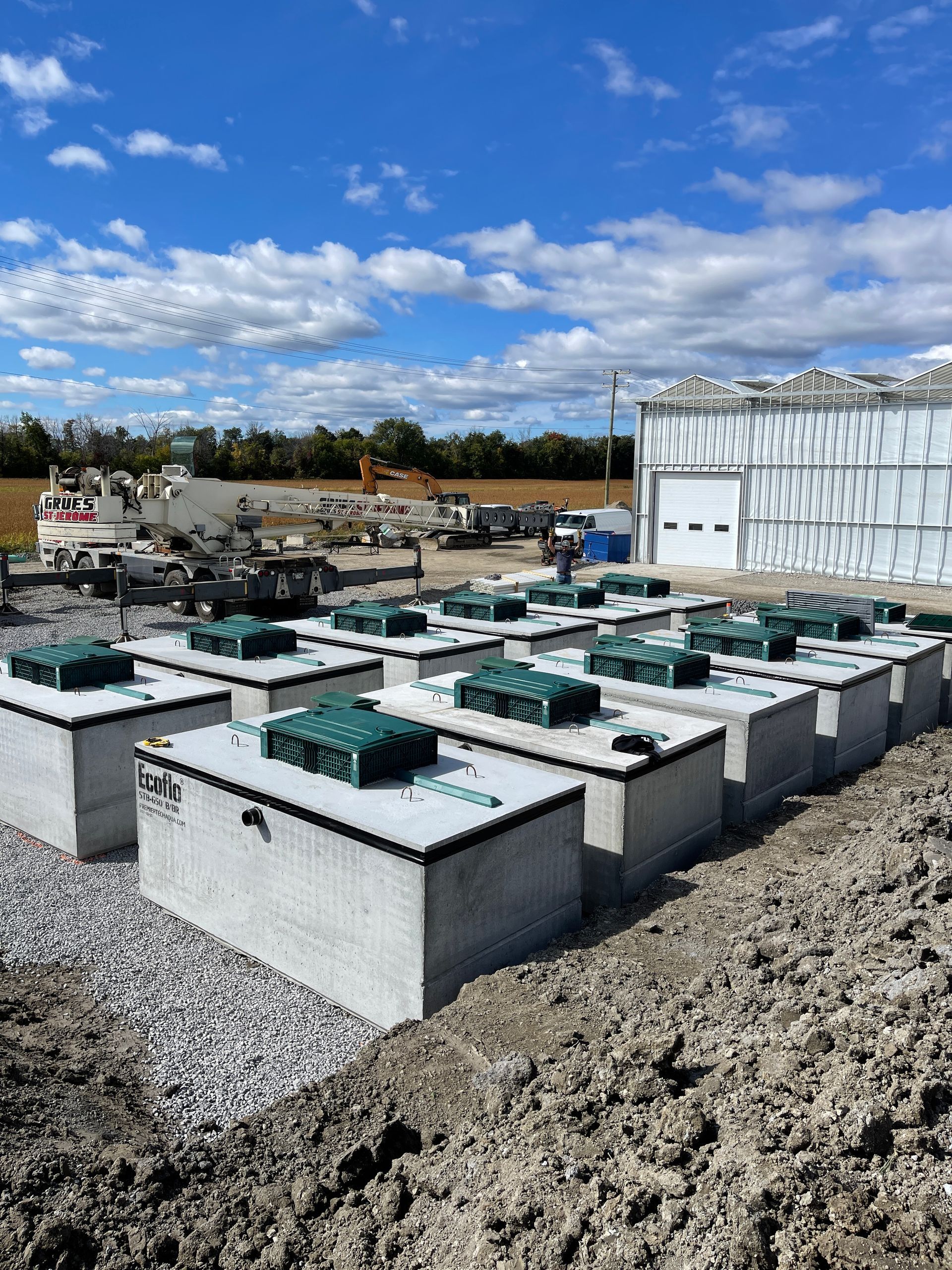 Une rangée de fosses septiques repose dans la terre devant un immeuble.