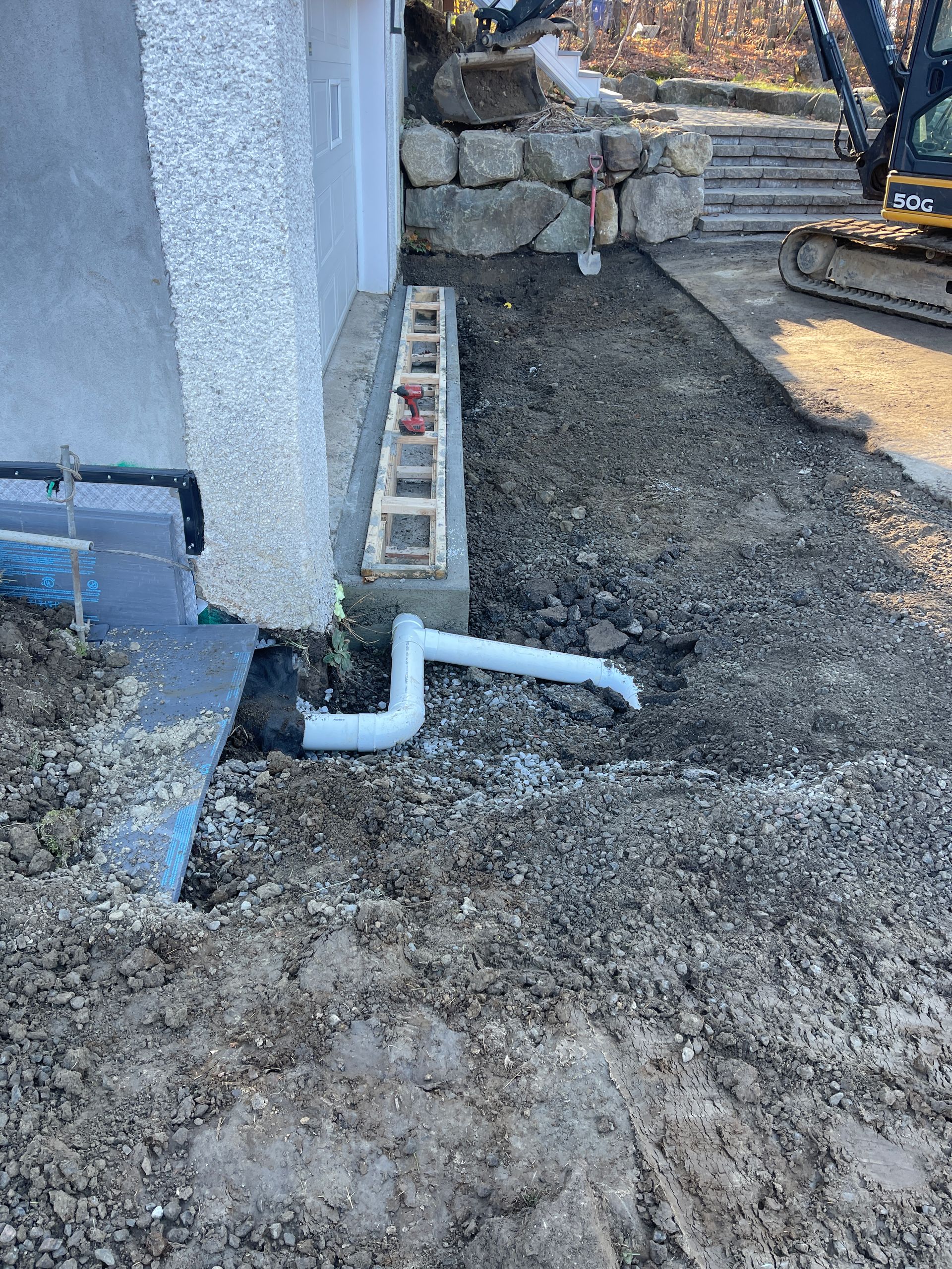 Un tuyau est en cours d'installation dans la terre à côté d'une maison.