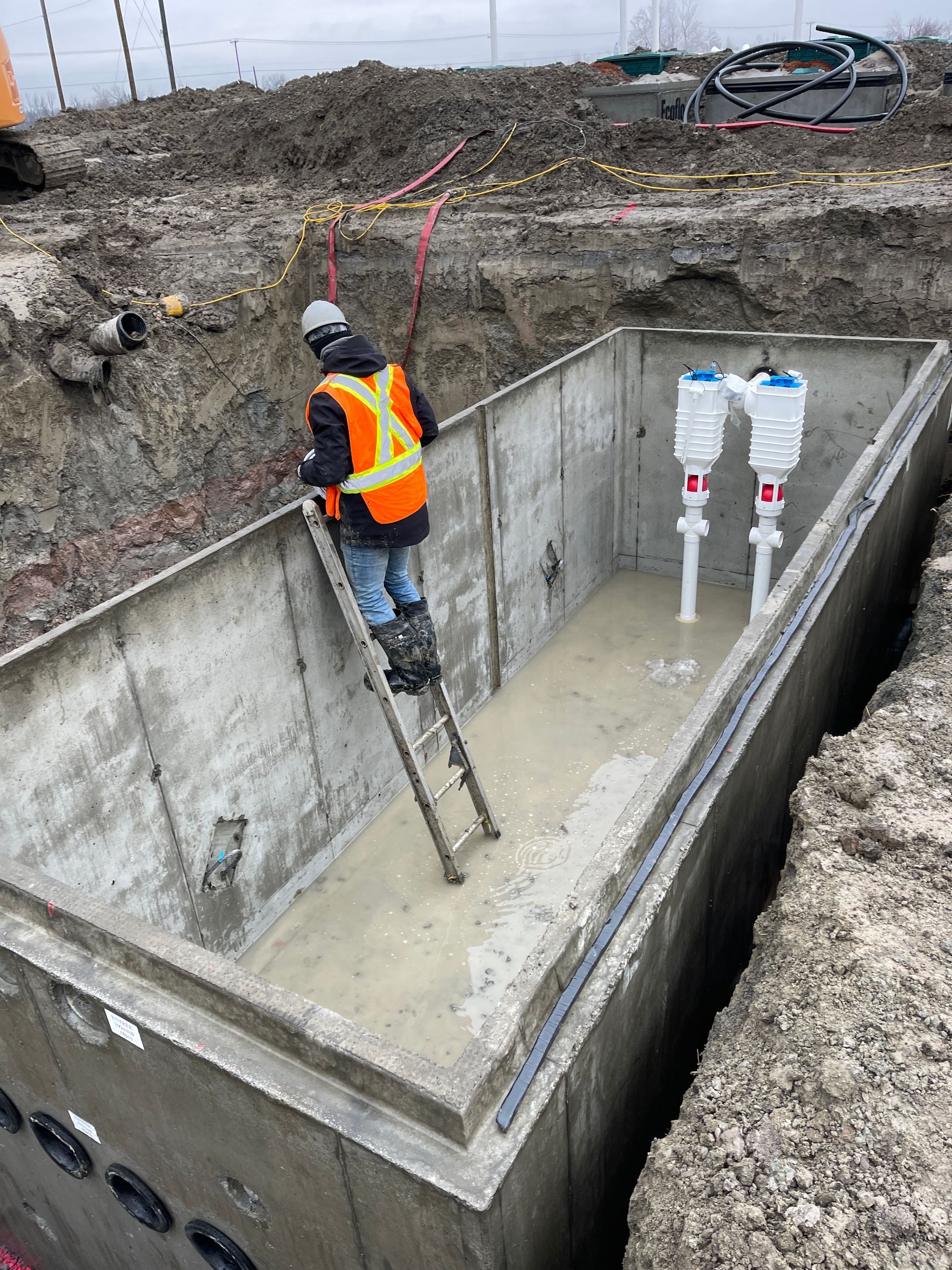 Un homme est debout sur une échelle dans une cuve en béton.