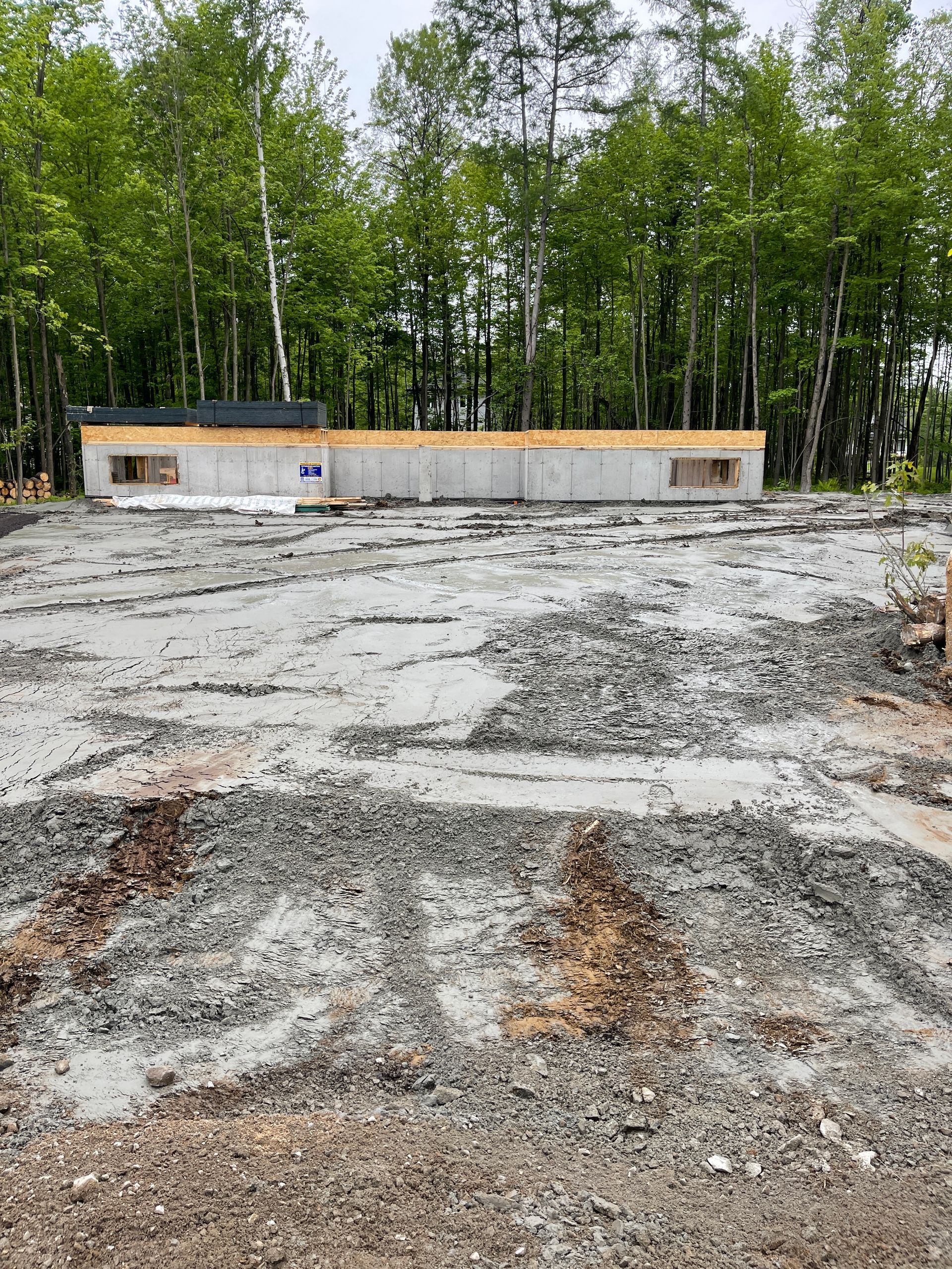 Un chantier de construction avec beaucoup de graviers et d'arbres en arrière-plan.
