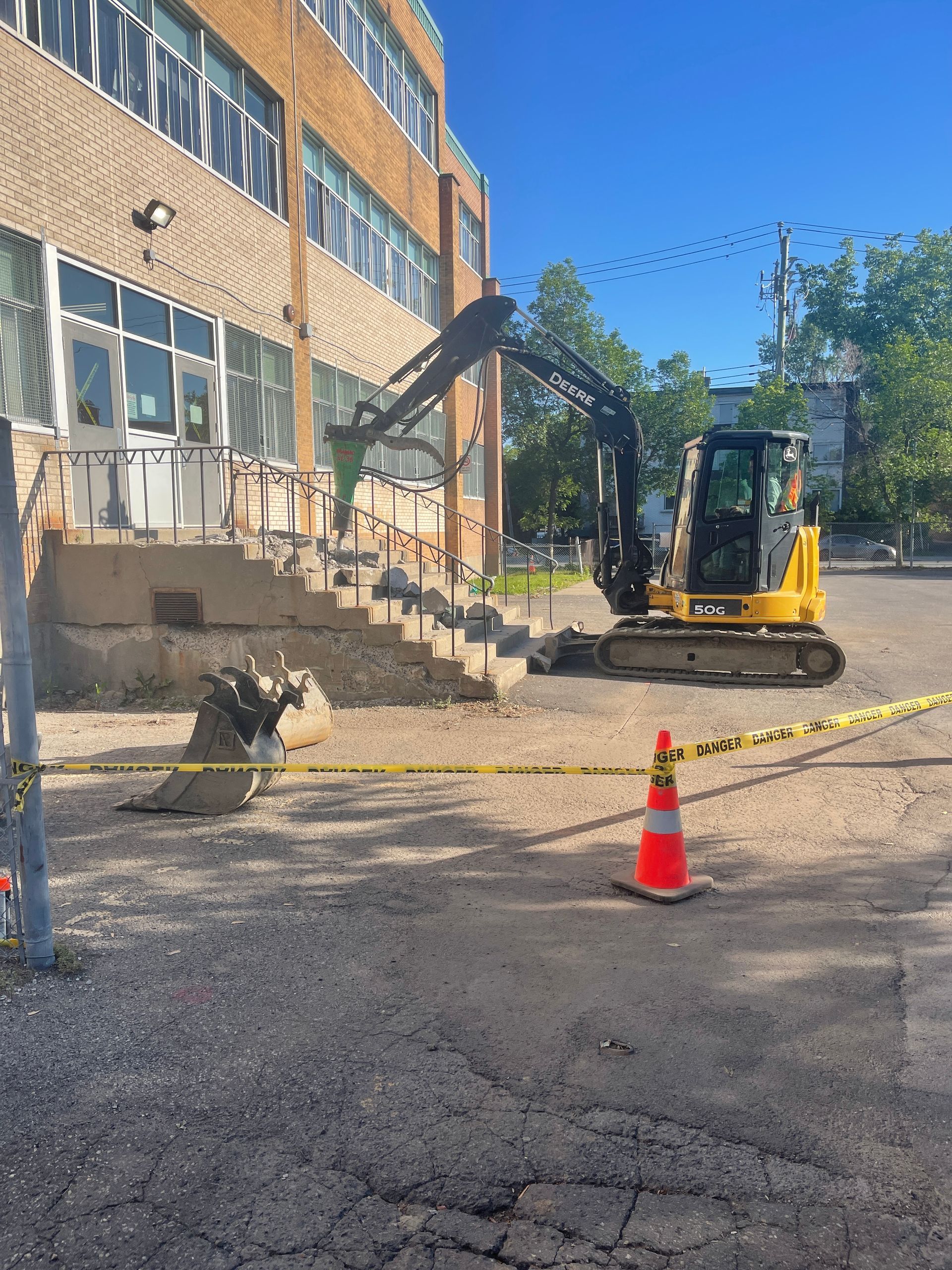 Une excavatrice jaune déplace de la terre devant un bâtiment