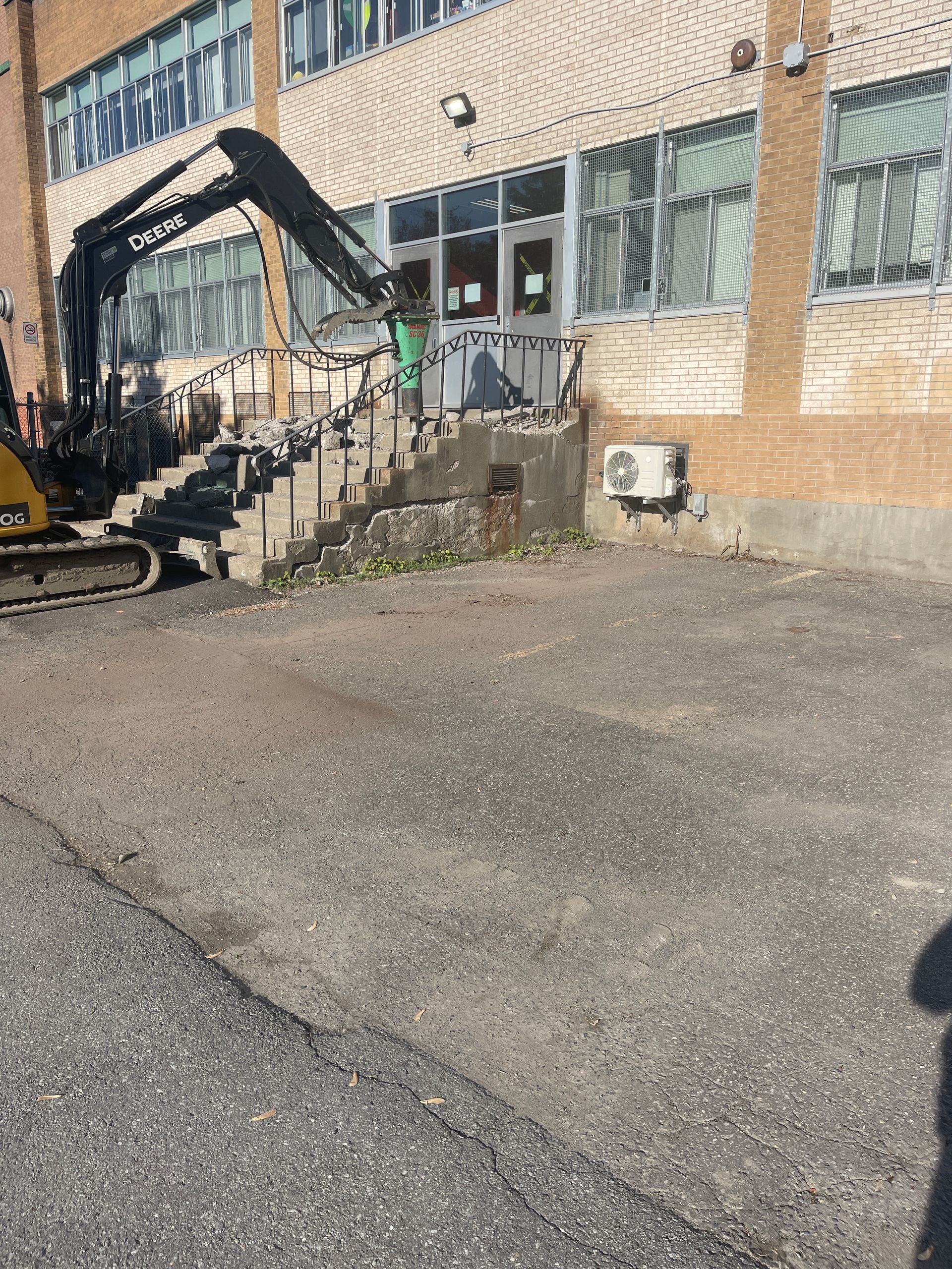 Une grosse pelle jaune est garée devant un immeuble.