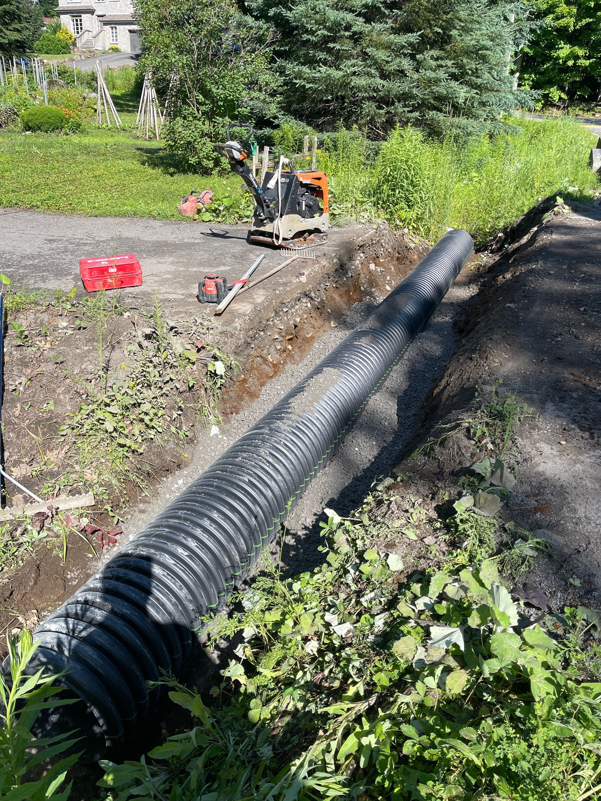 Un gros tuyau noir se trouve au milieu d’un champ de terre.