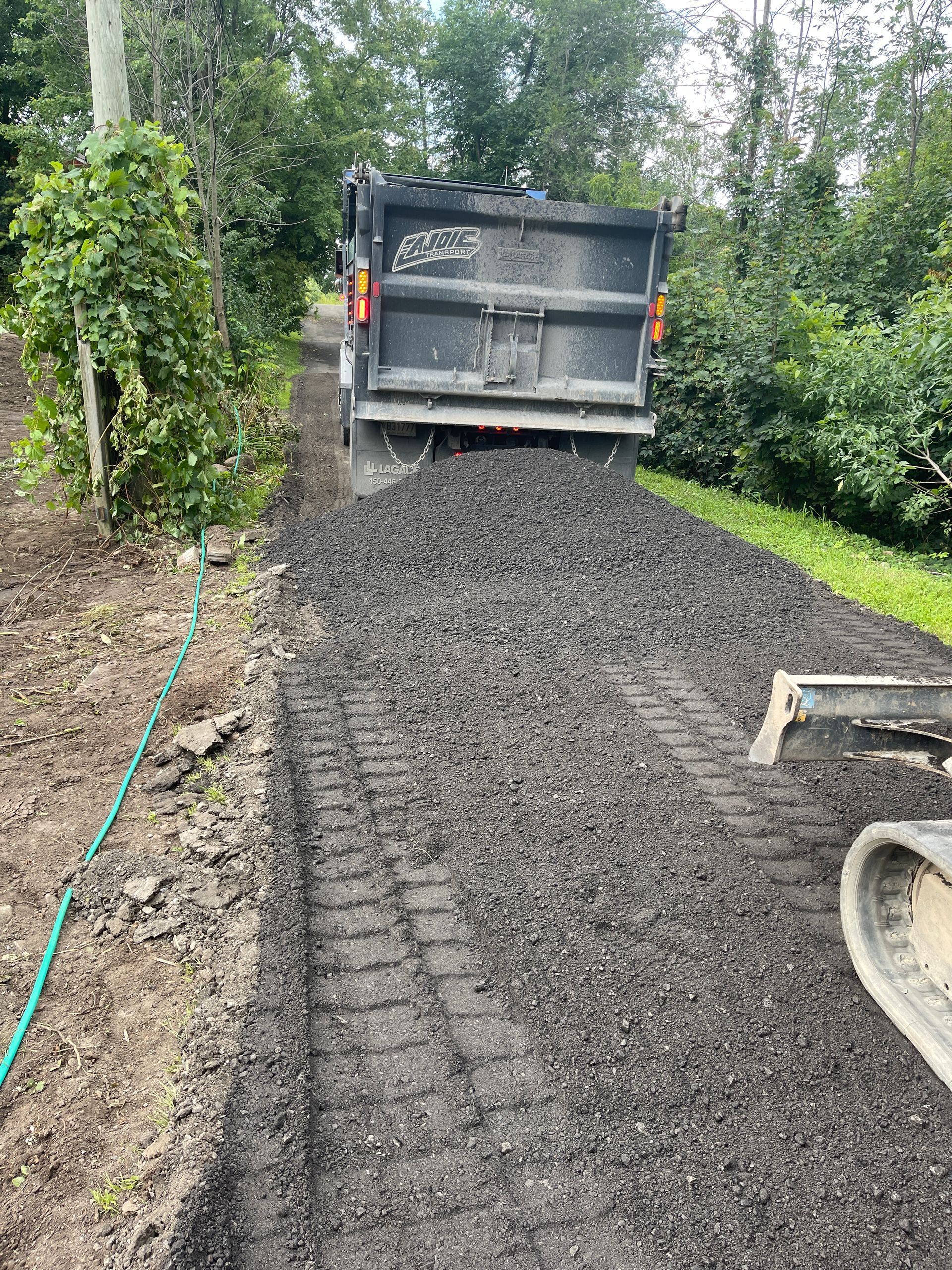 Un camion-benne roule sur un chemin de terre.