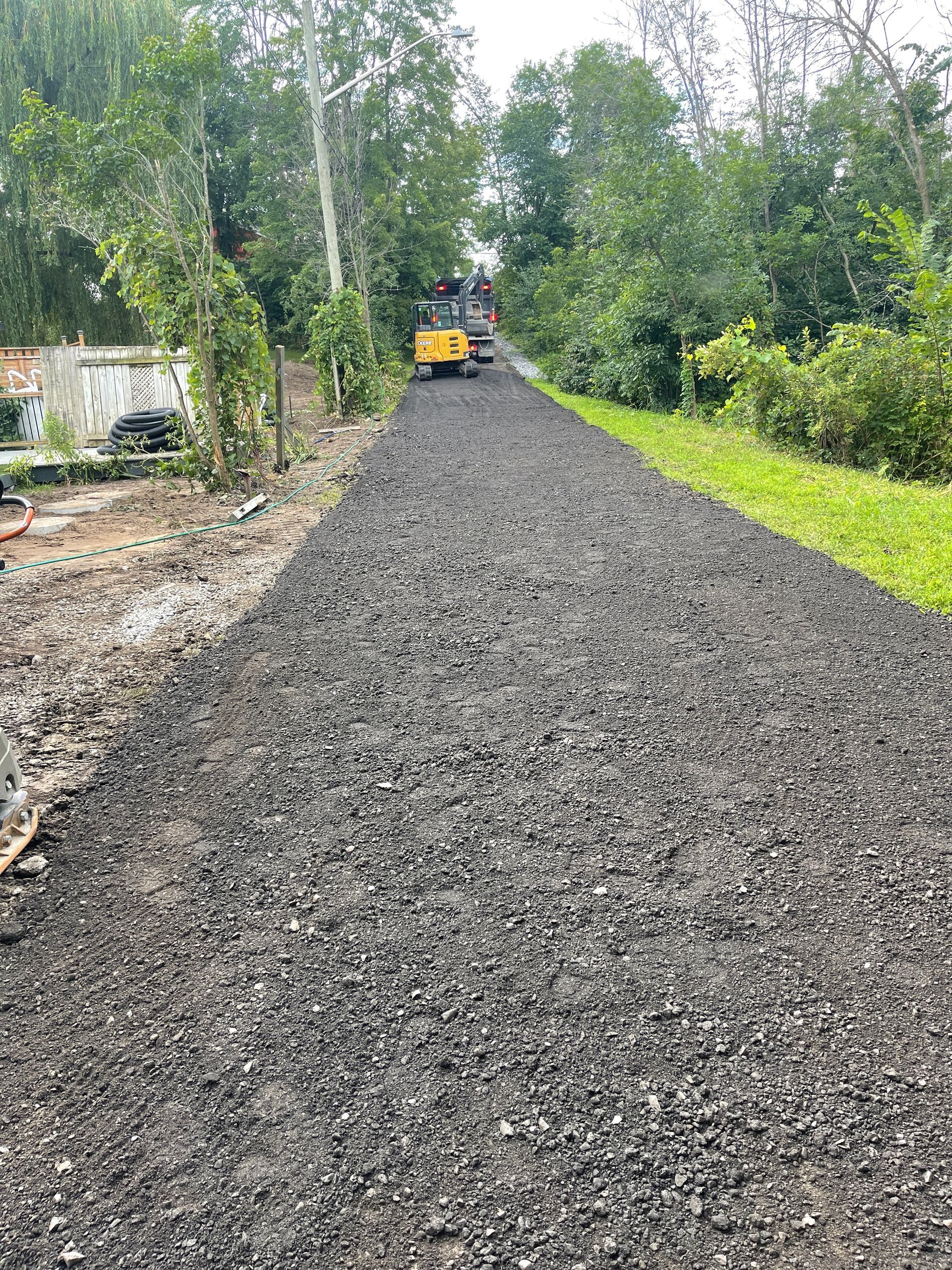 Un camion roule sur une route de gravier entourée d'arbres.