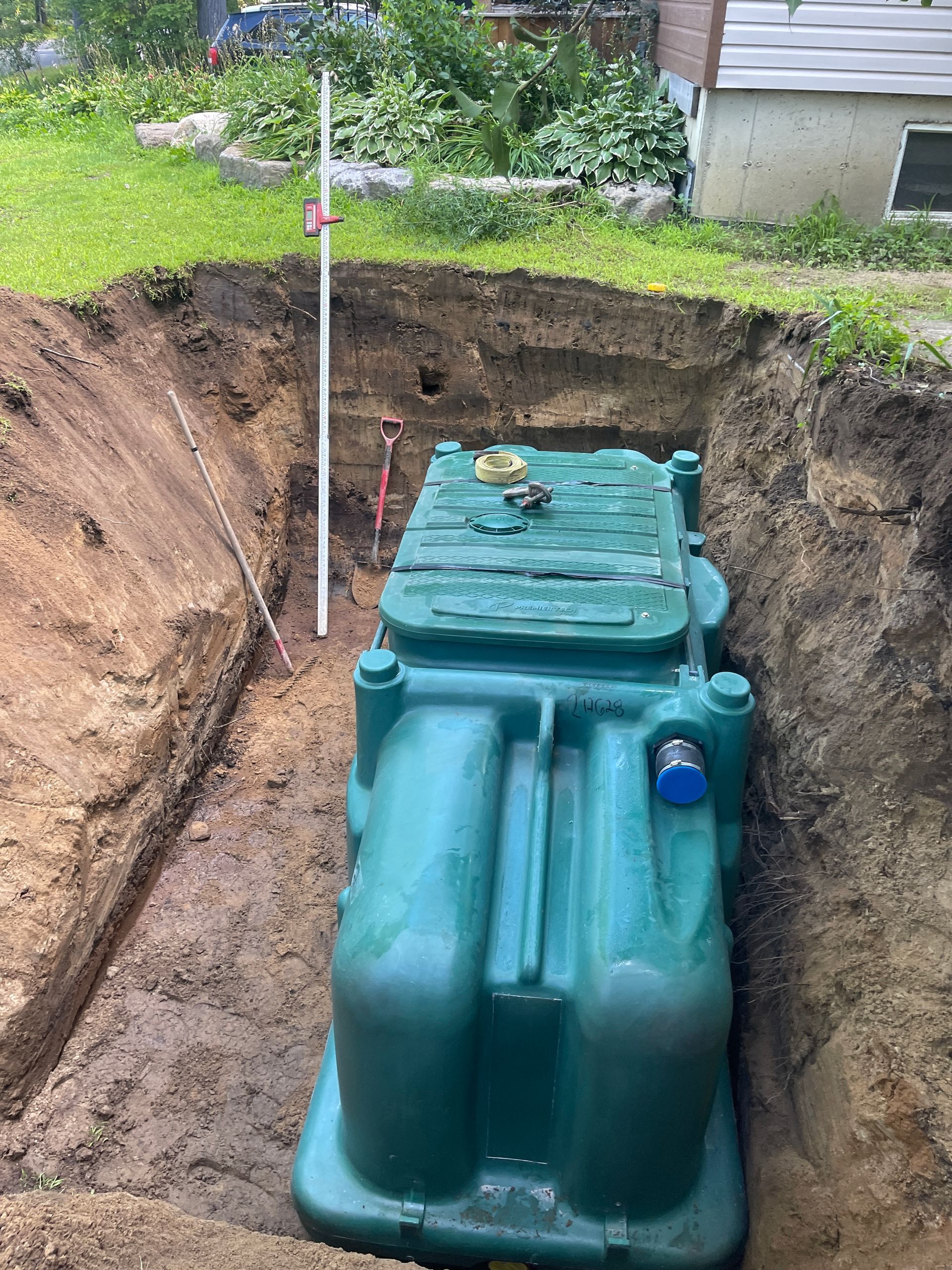 Un grand réservoir vert se trouve dans un trou dans le sol.