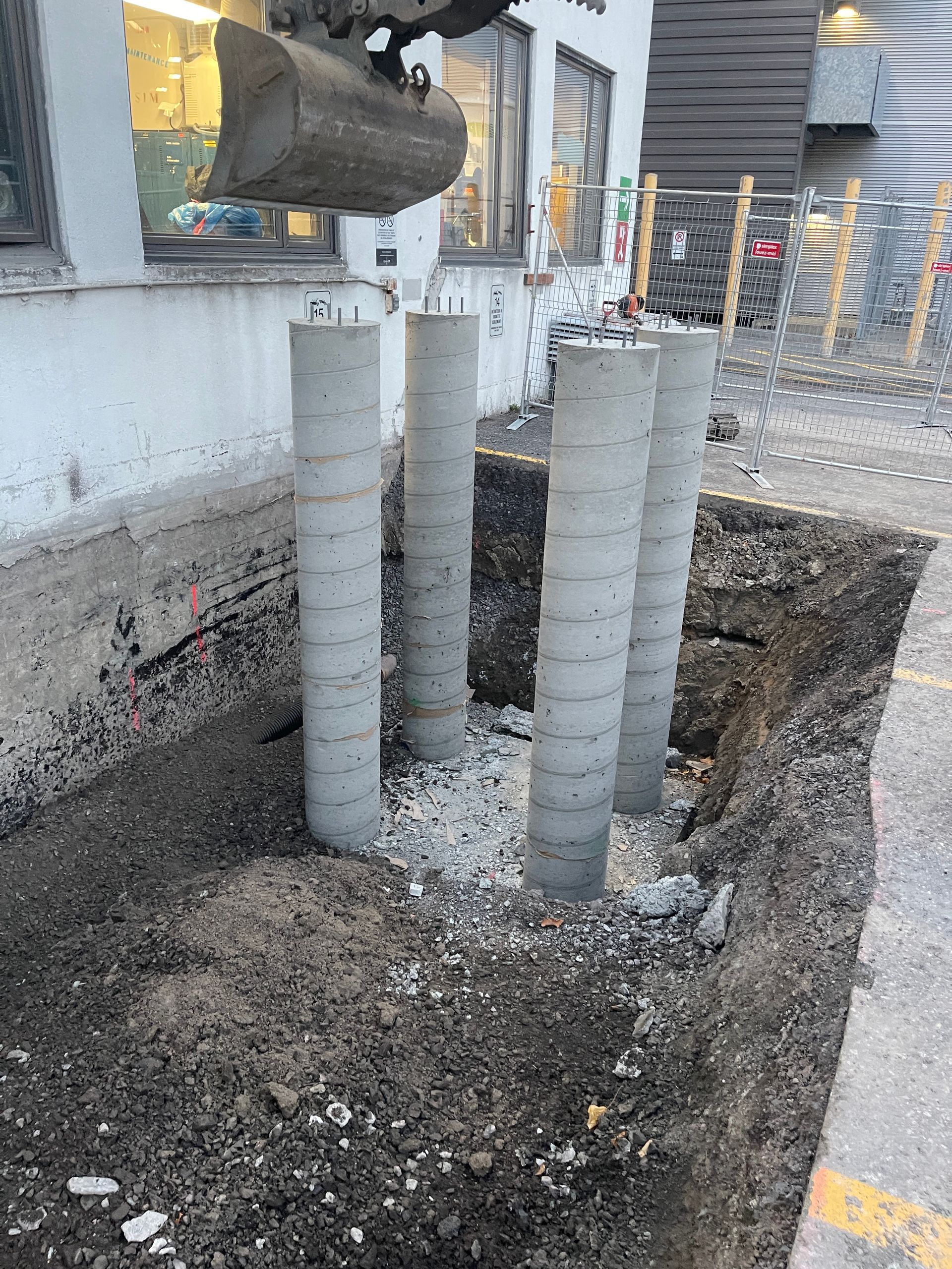 Un bulldozer creuse un trou dans le sol devant un immeuble.