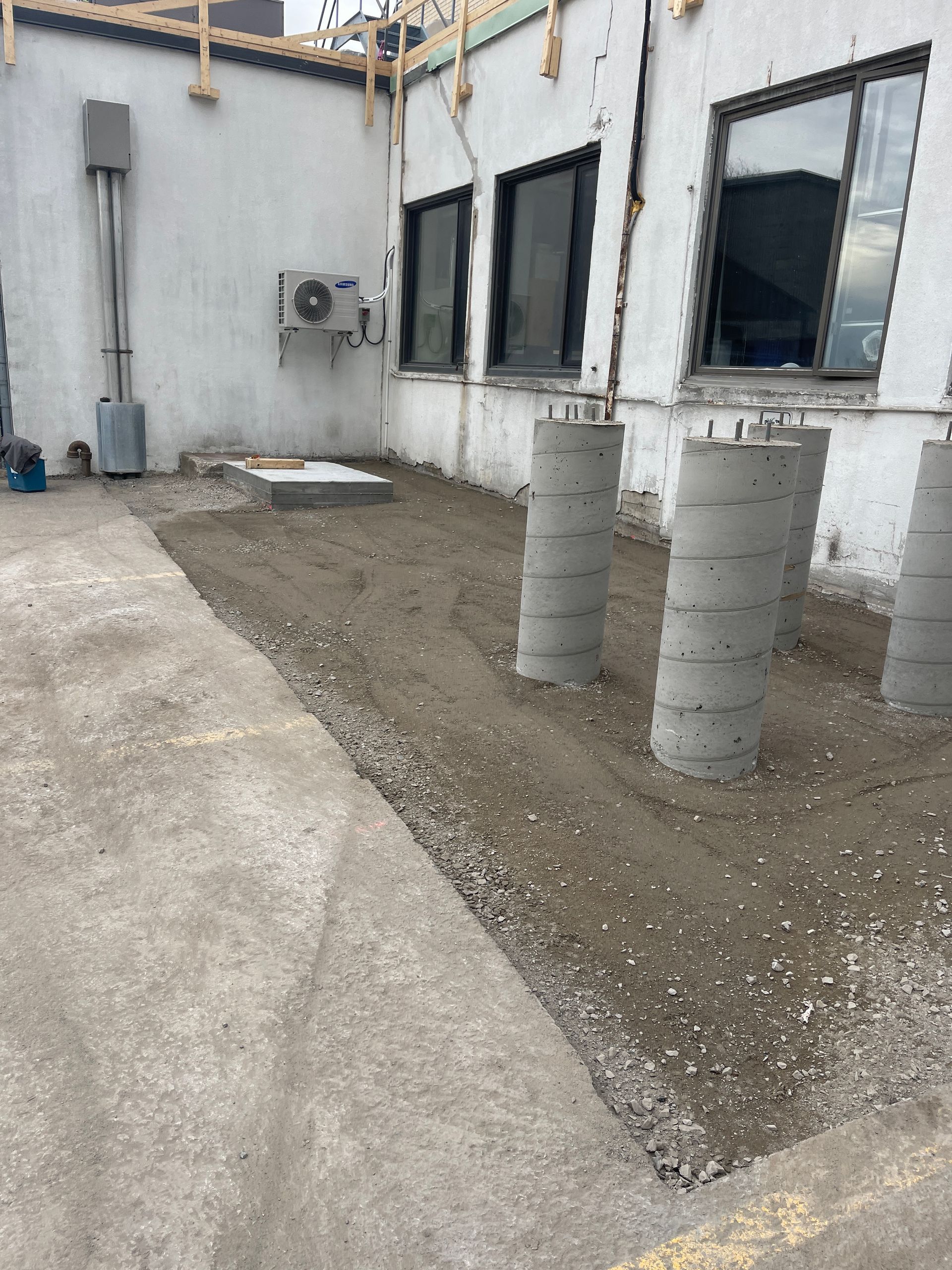 Un bâtiment en construction avec des piliers en béton devant lui