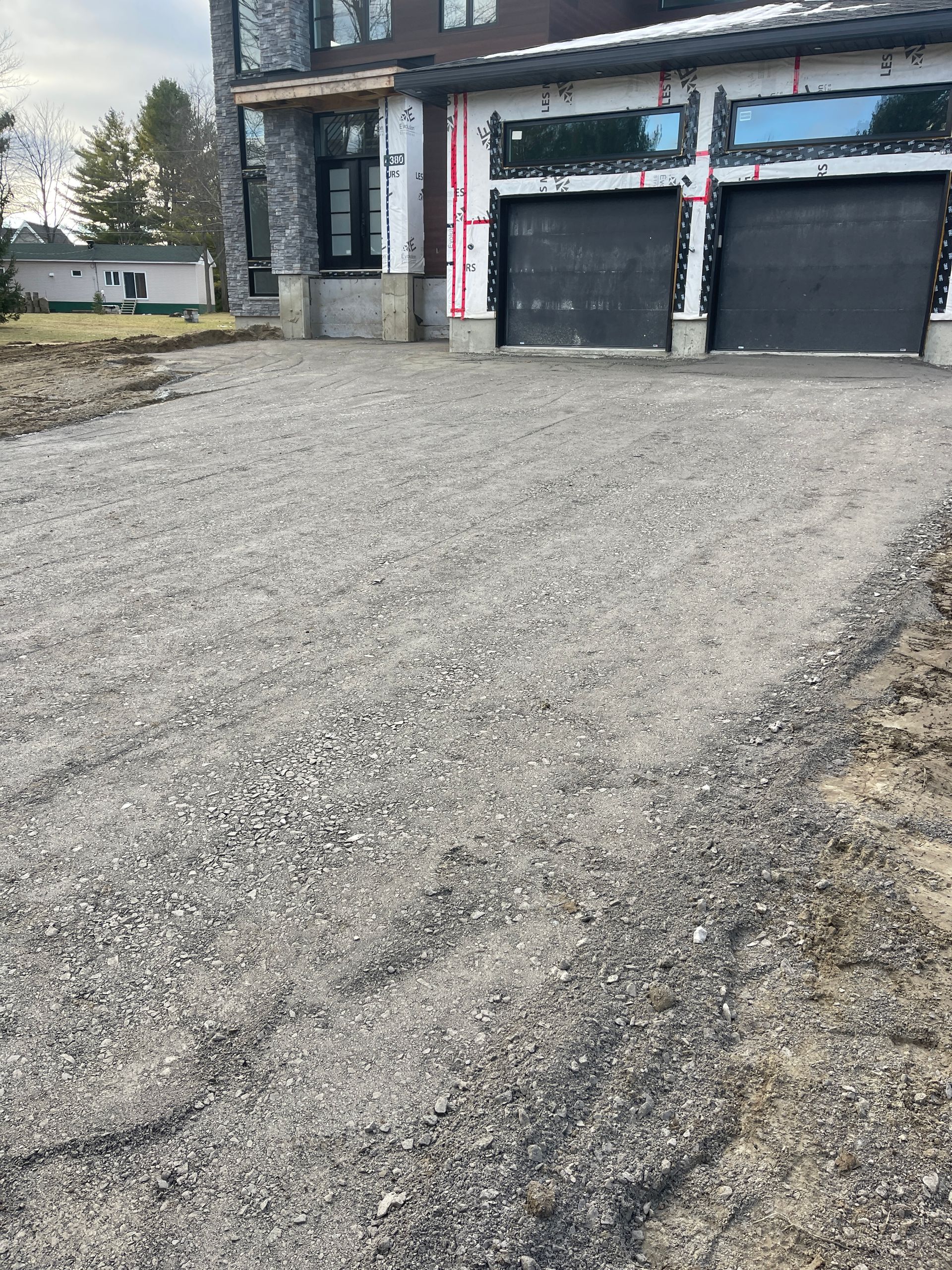 Une allée en gravier menant à une maison avec deux portes de garage.