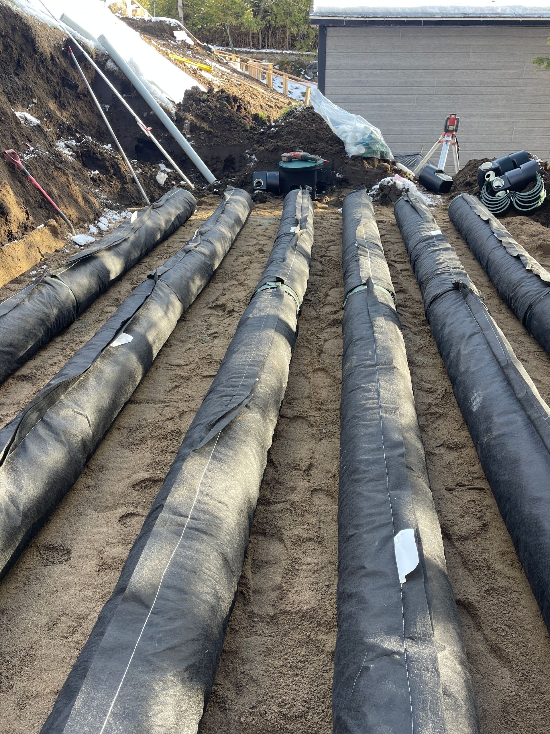 Une rangée de tuyaux noirs est alignée dans la terre.