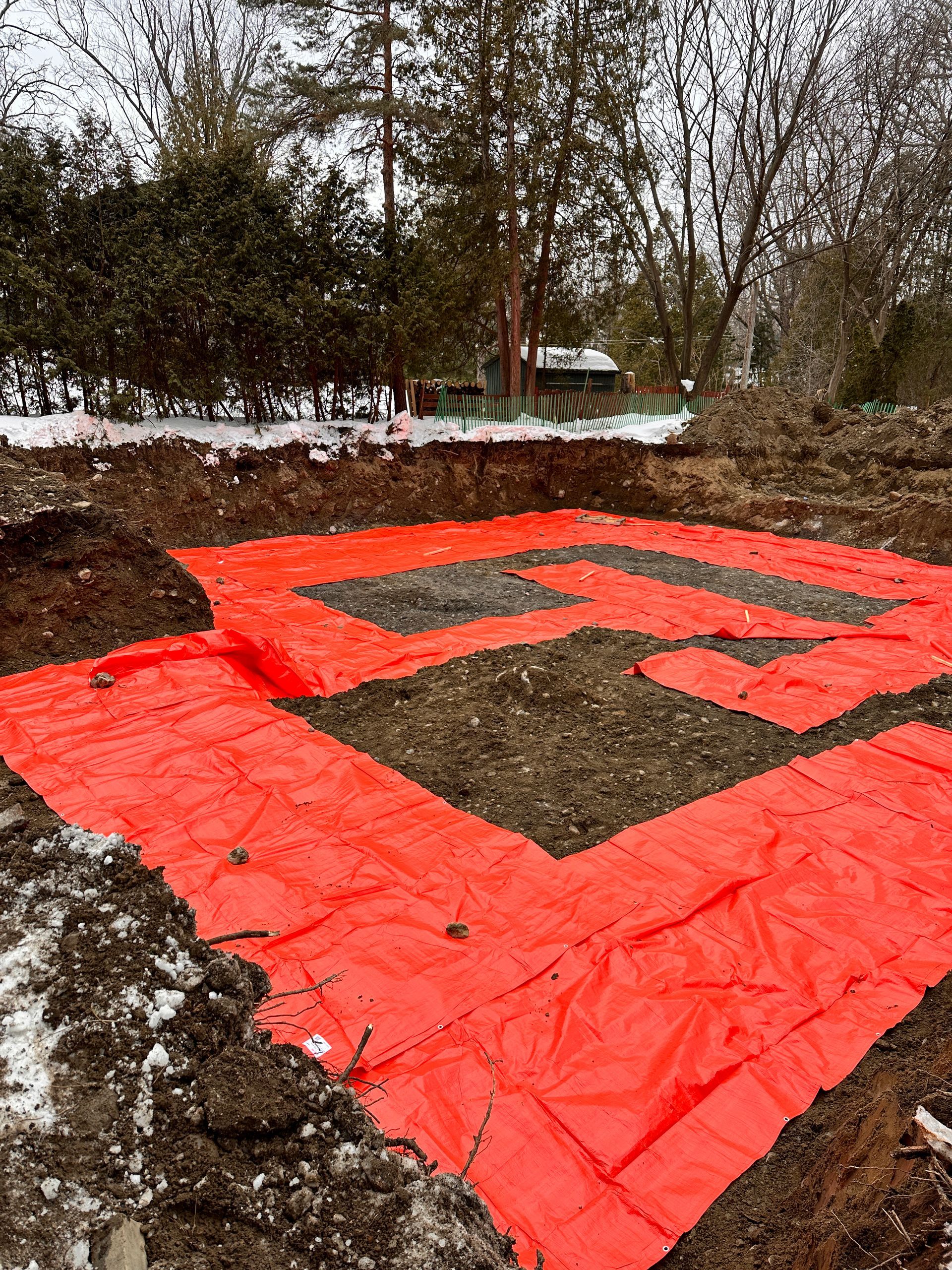 Une grande bâche orange recouvre un champ de terre.