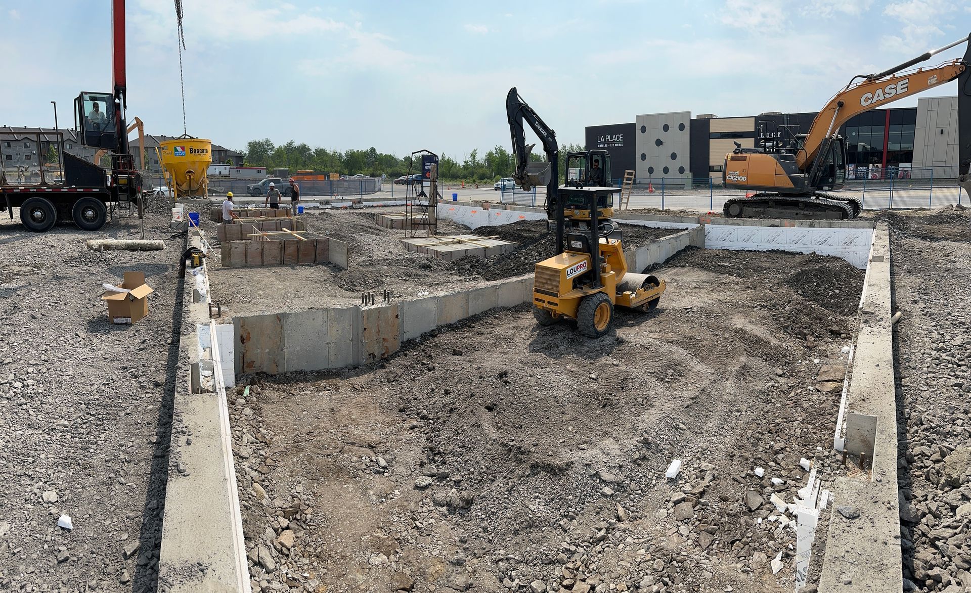 Un chantier de construction avec un chariot élévateur et une grue en arrière-plan.