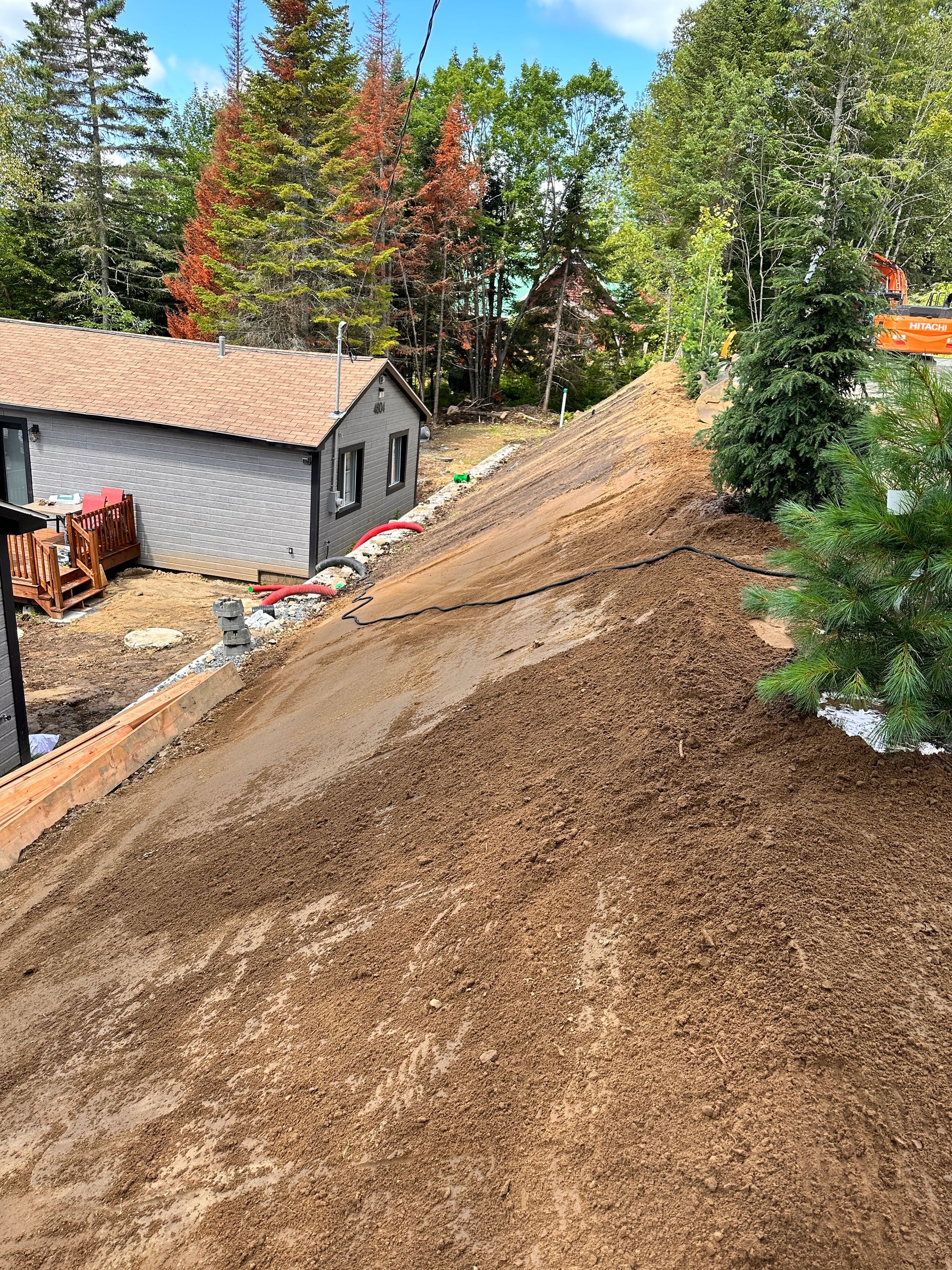 Une maison est située au sommet d’une colline de terre entourée d’arbres.