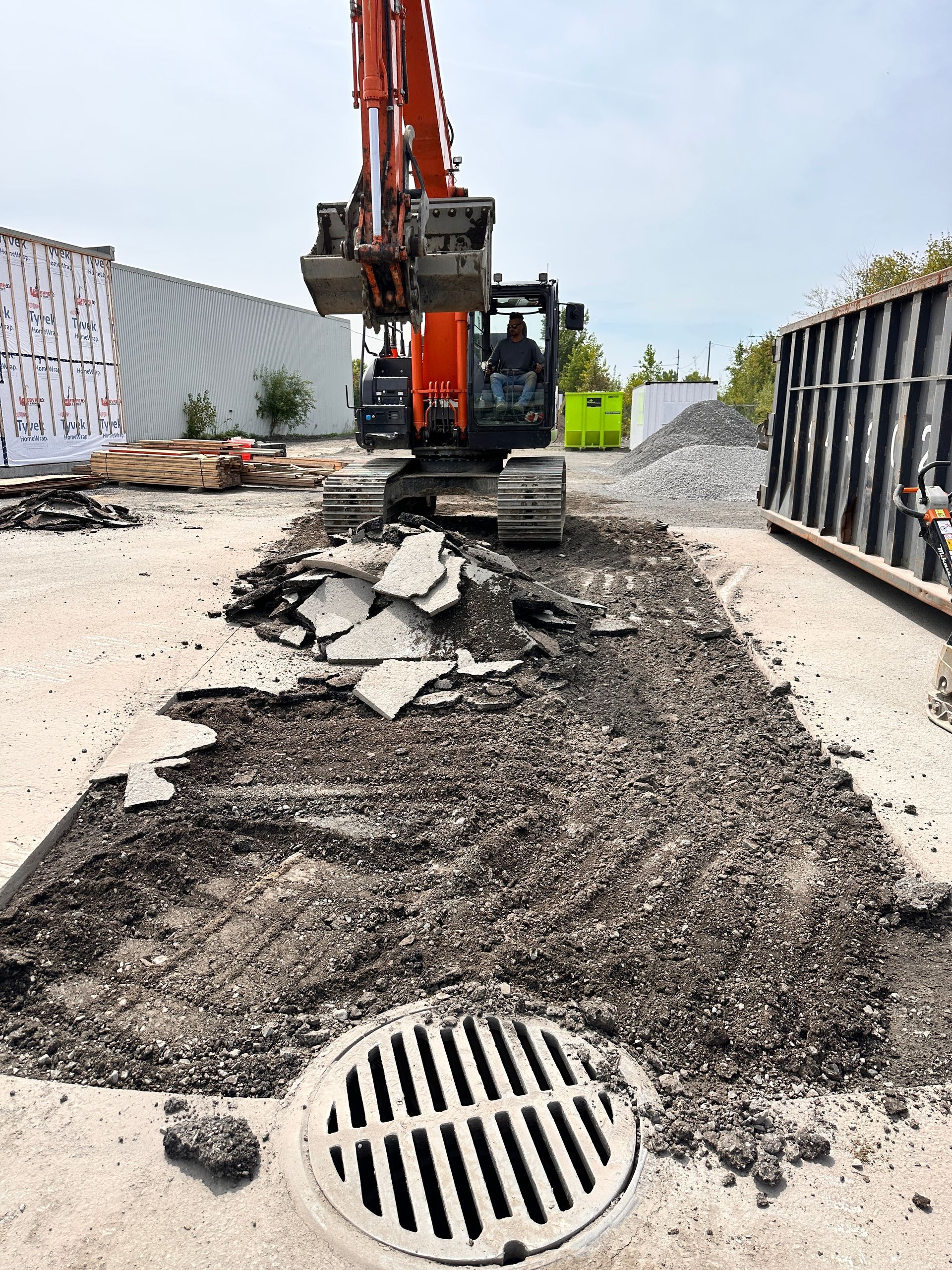 Un couvercle de trou d'homme est en train d'être retiré par une excavatrice.