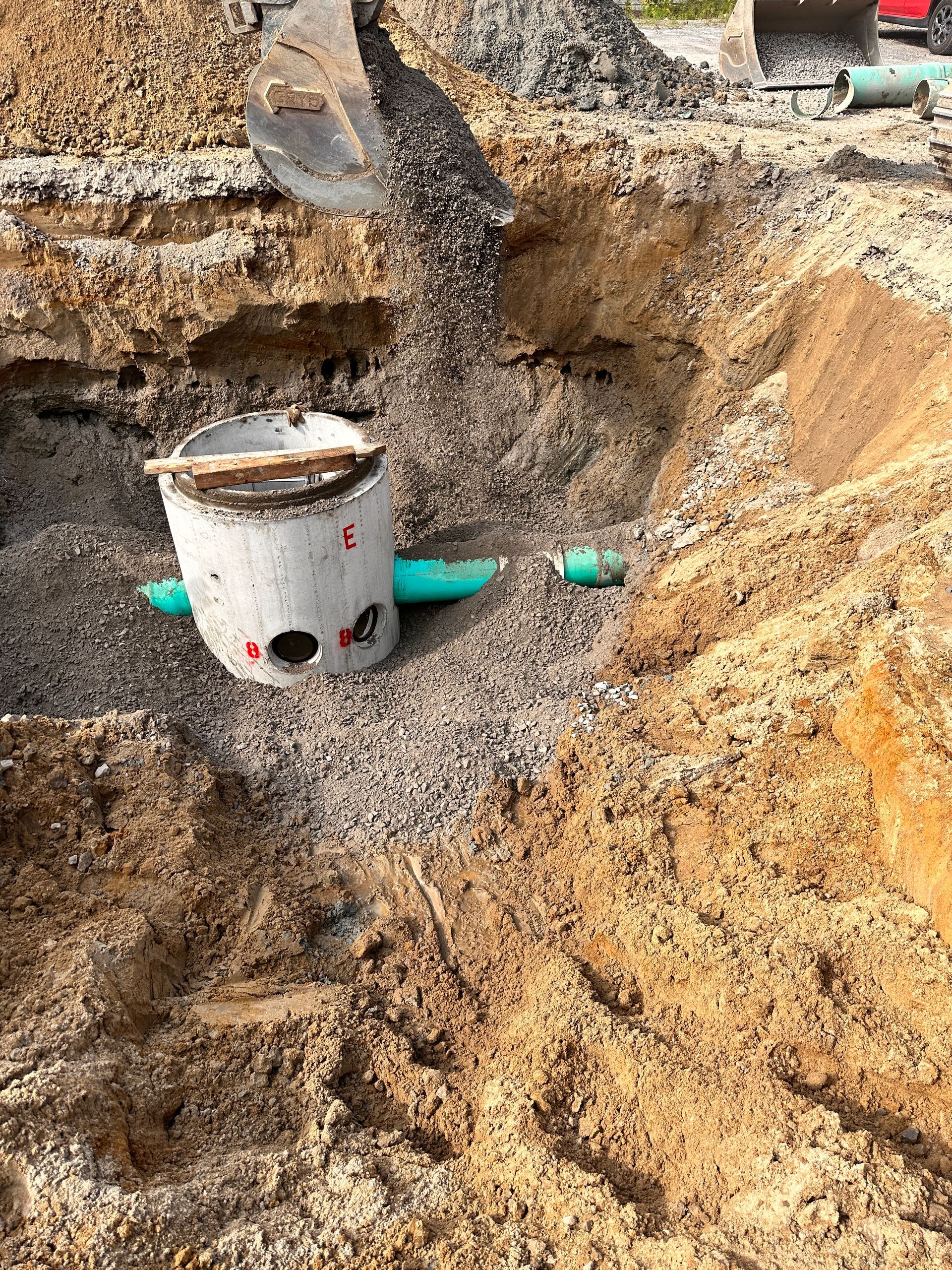 Une plaque d'égout est coulée dans un trou creusé dans le sol.
