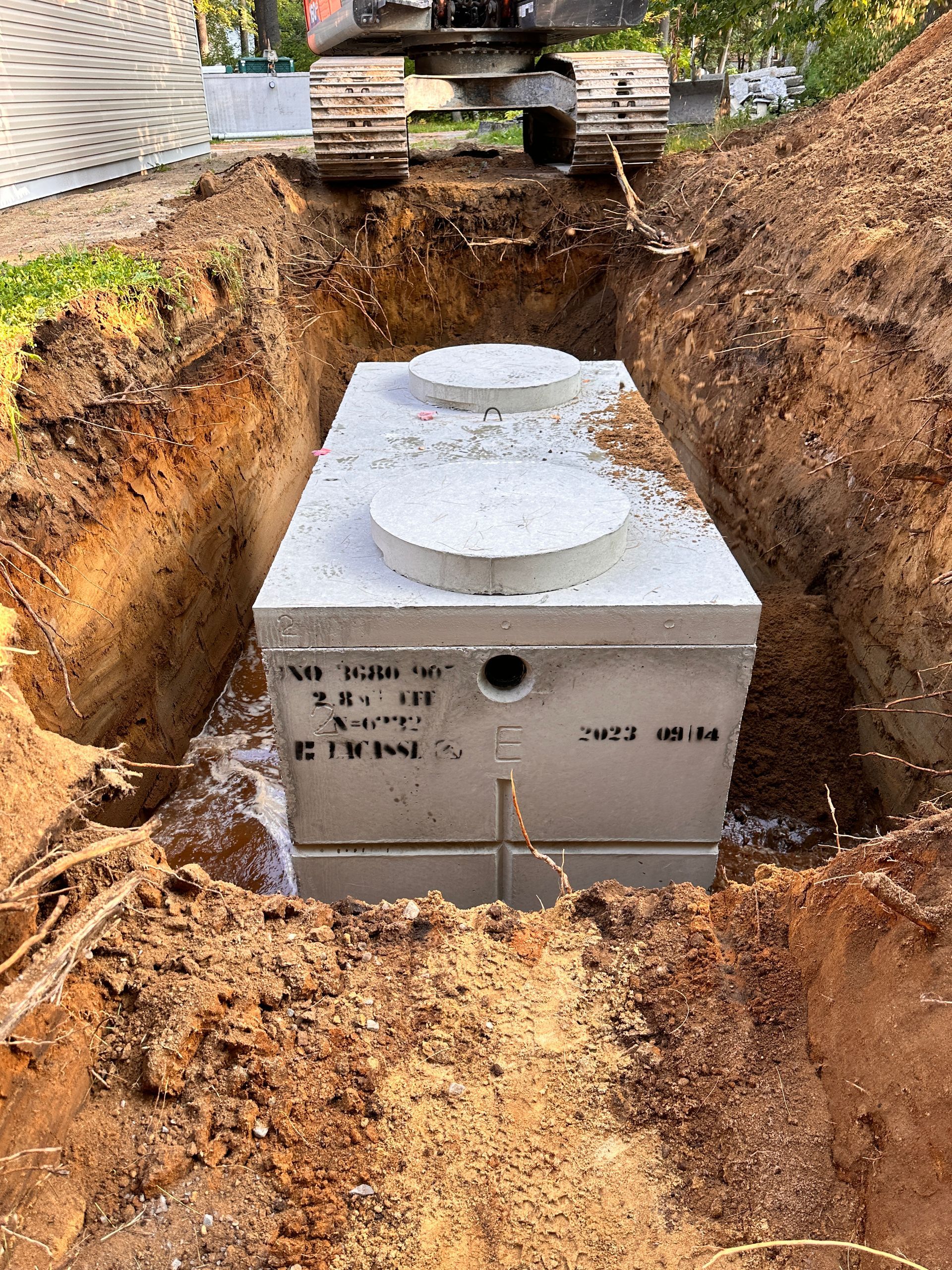Une fosse septique est en cours d'installation dans un trou creusé dans le sol.