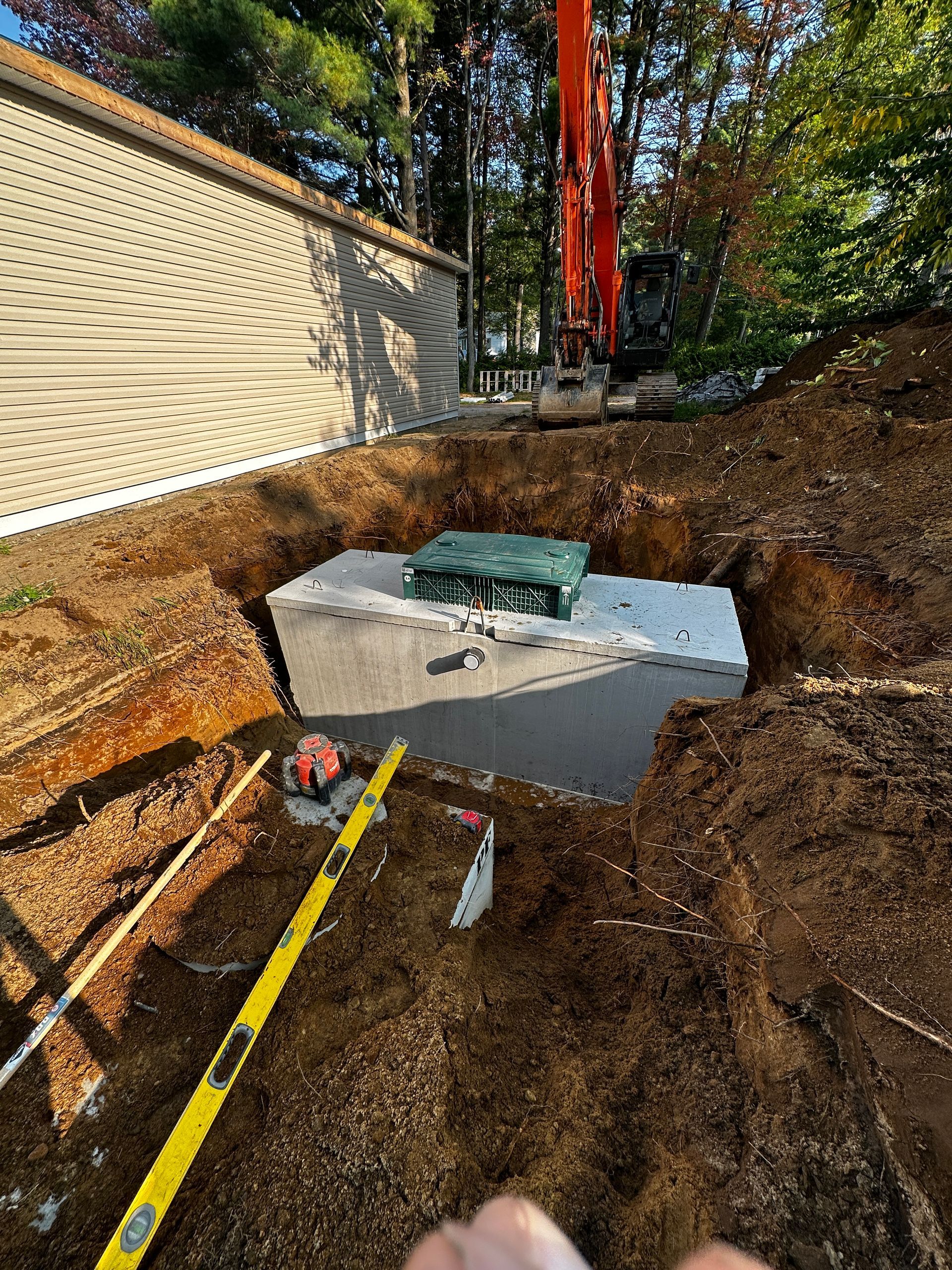 Une grosse excavatrice creuse un trou dans le sol à côté d’une maison.