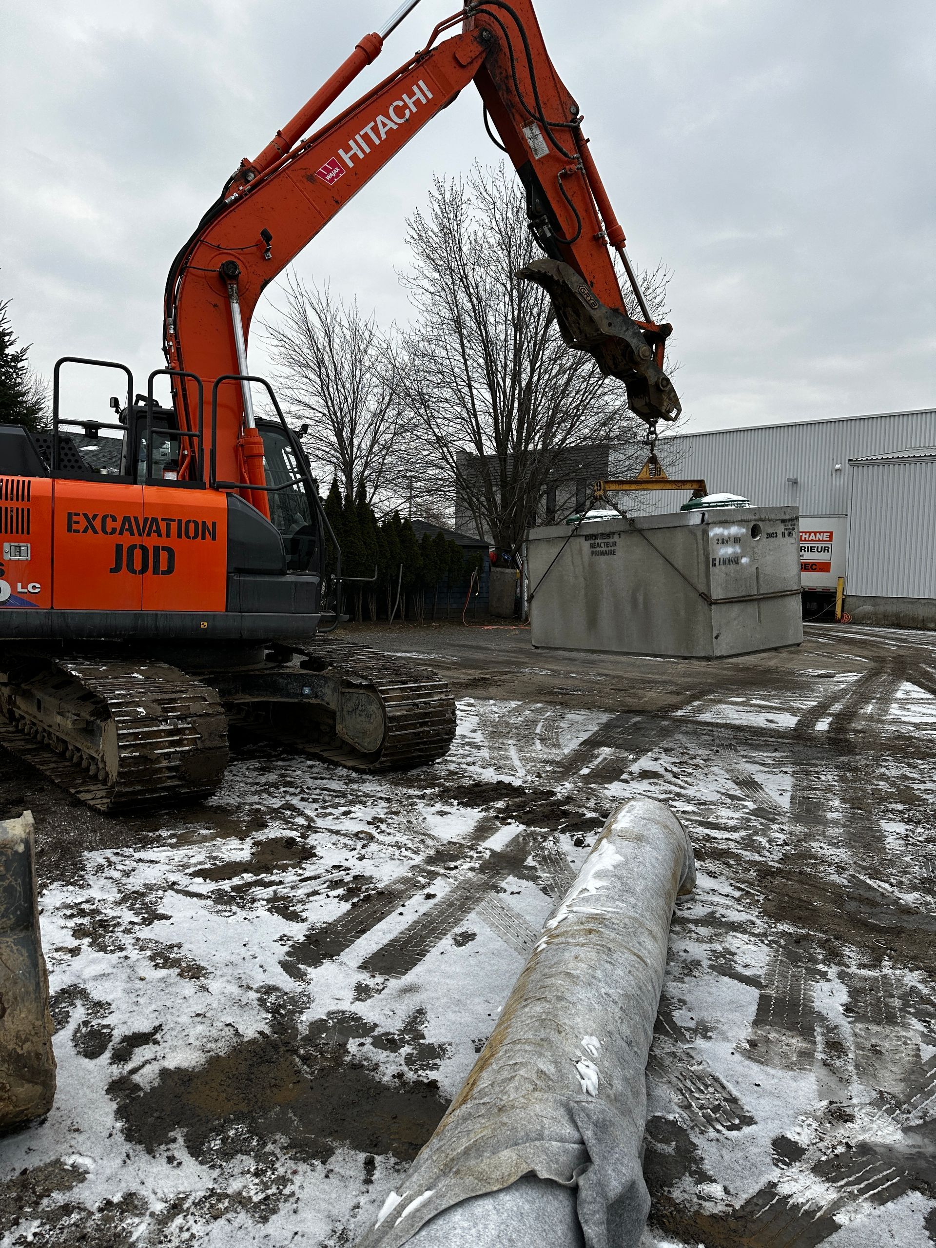 Une grande excavatrice travaille sur un chantier de construction dans la neige.