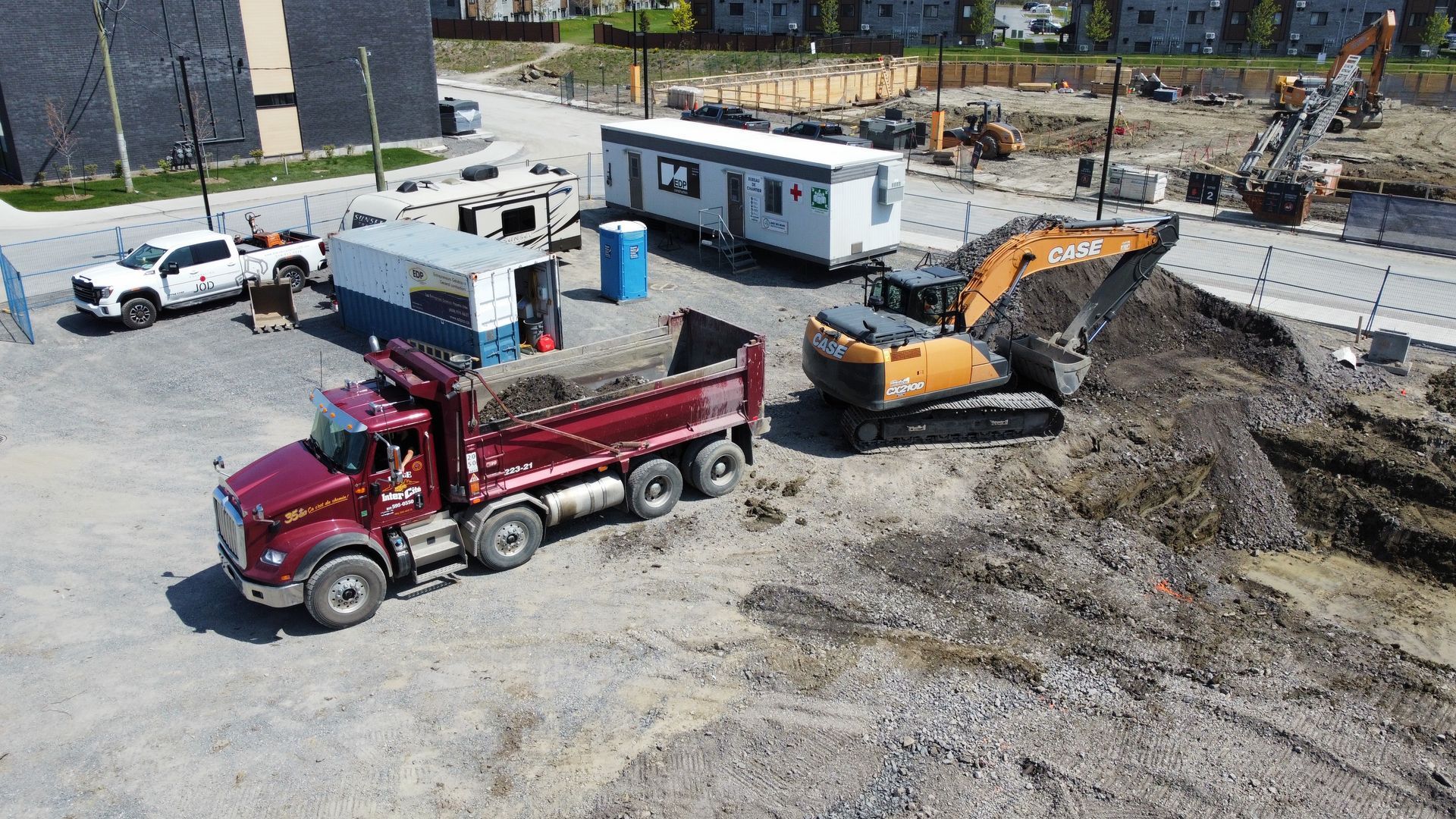Une vue aérienne d'un chantier de construction avec un camion-benne et une excavatrice.
