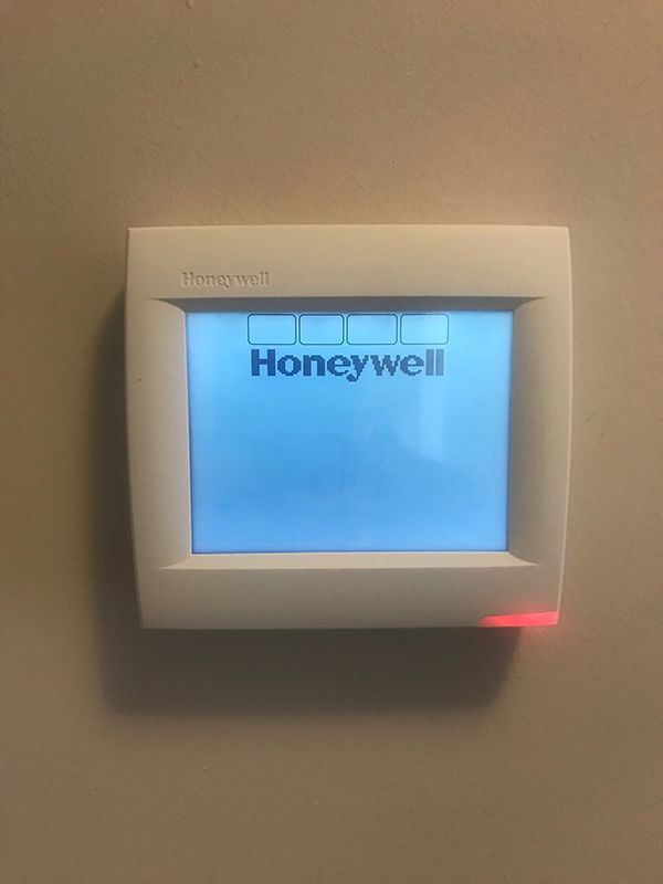 A honeywell thermostat is hanging on a wall.