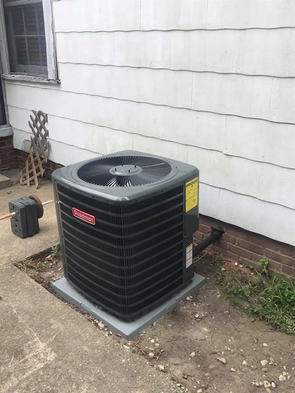 An air conditioner is sitting on the side of a house.