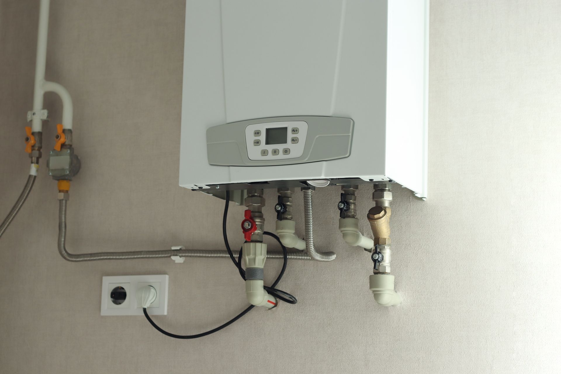 A white boiler is hanging on a wall with pipes attached to it.