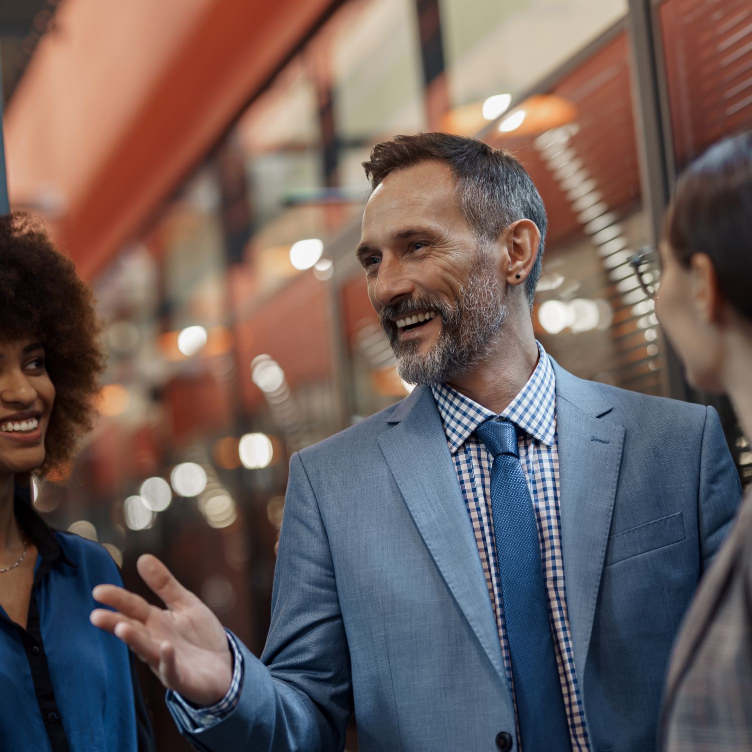 A man in a suit and tie is talking to two women.