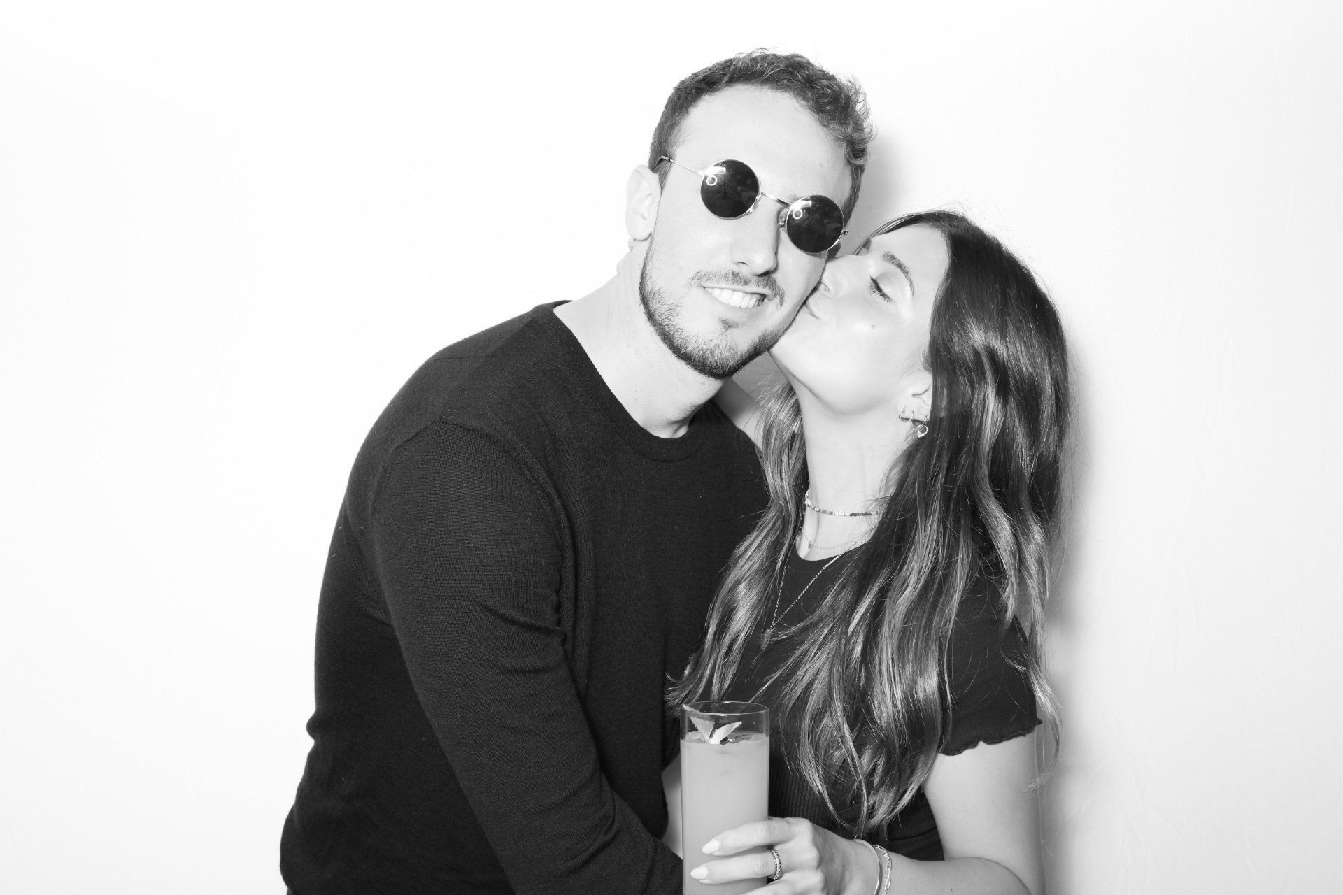 A woman is kissing a man on the cheek in a black and white photo.