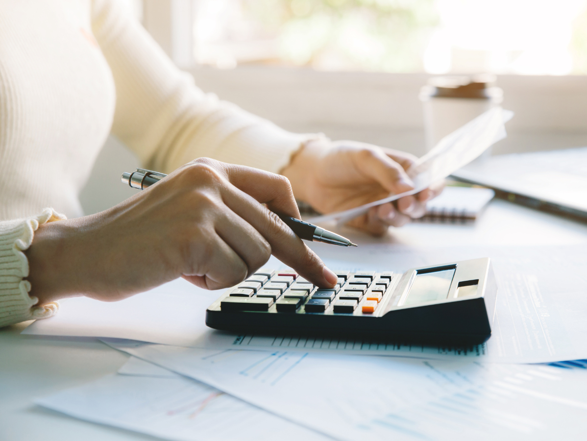 Hands using a calculator and pen over paperwork on a desk