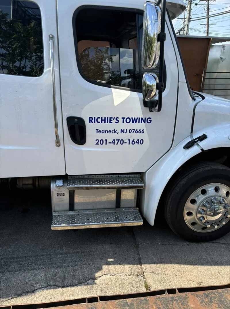 A white towing truck is parked on the side of the road.
