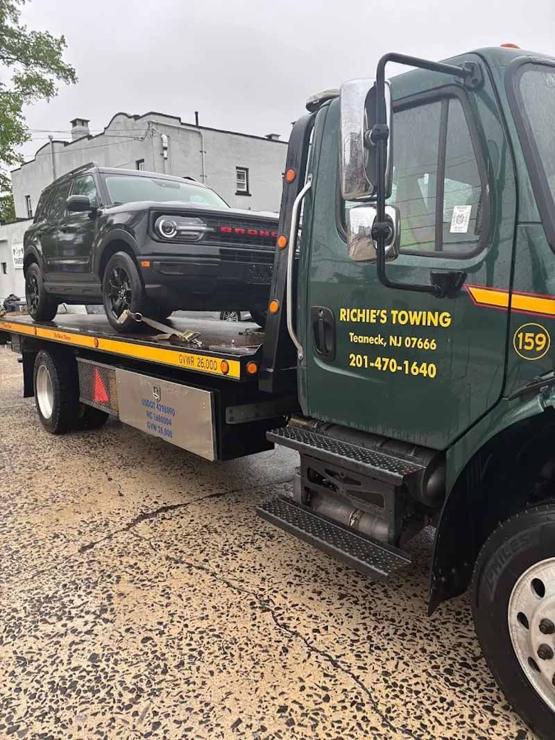 A tow truck is carrying a car on the back of it.