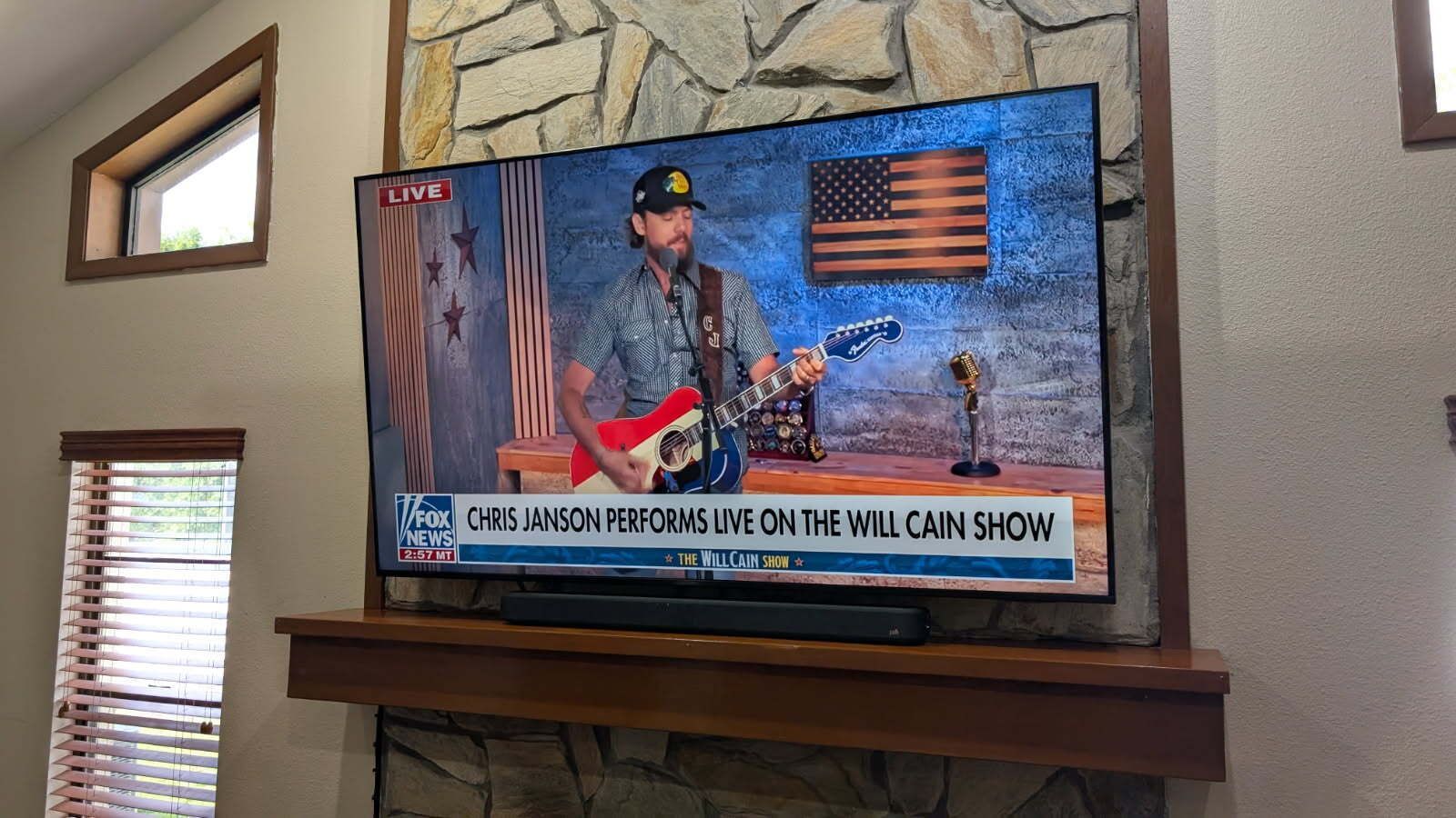 A man is playing a guitar on a television in a living room.
