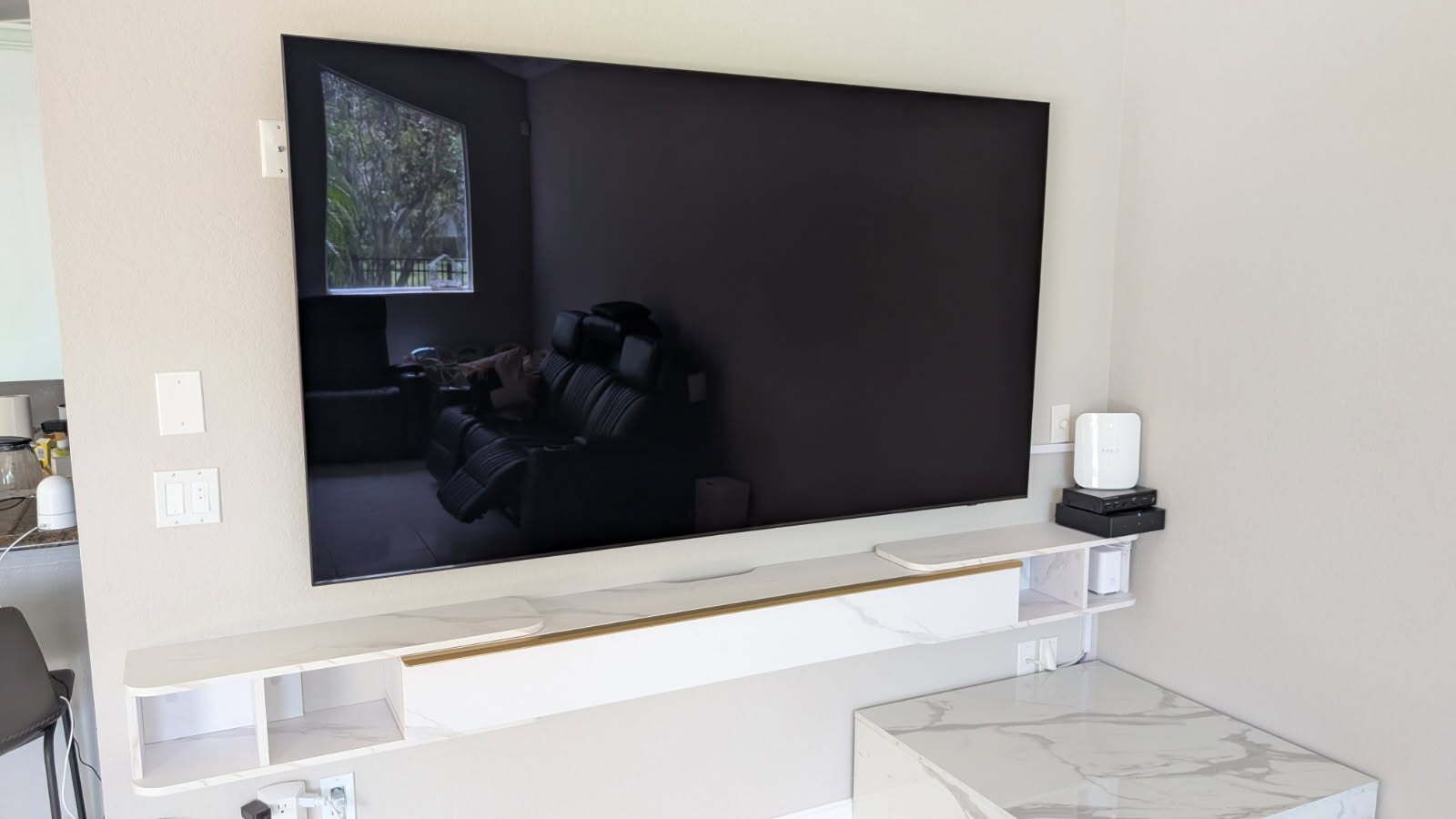 A large flat screen tv is mounted on a wall in a living room.