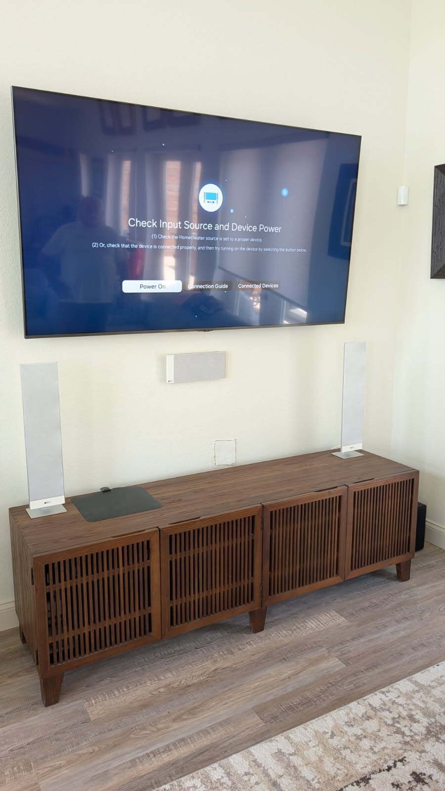 A living room with a flat screen tv on the wall and a wooden entertainment center.