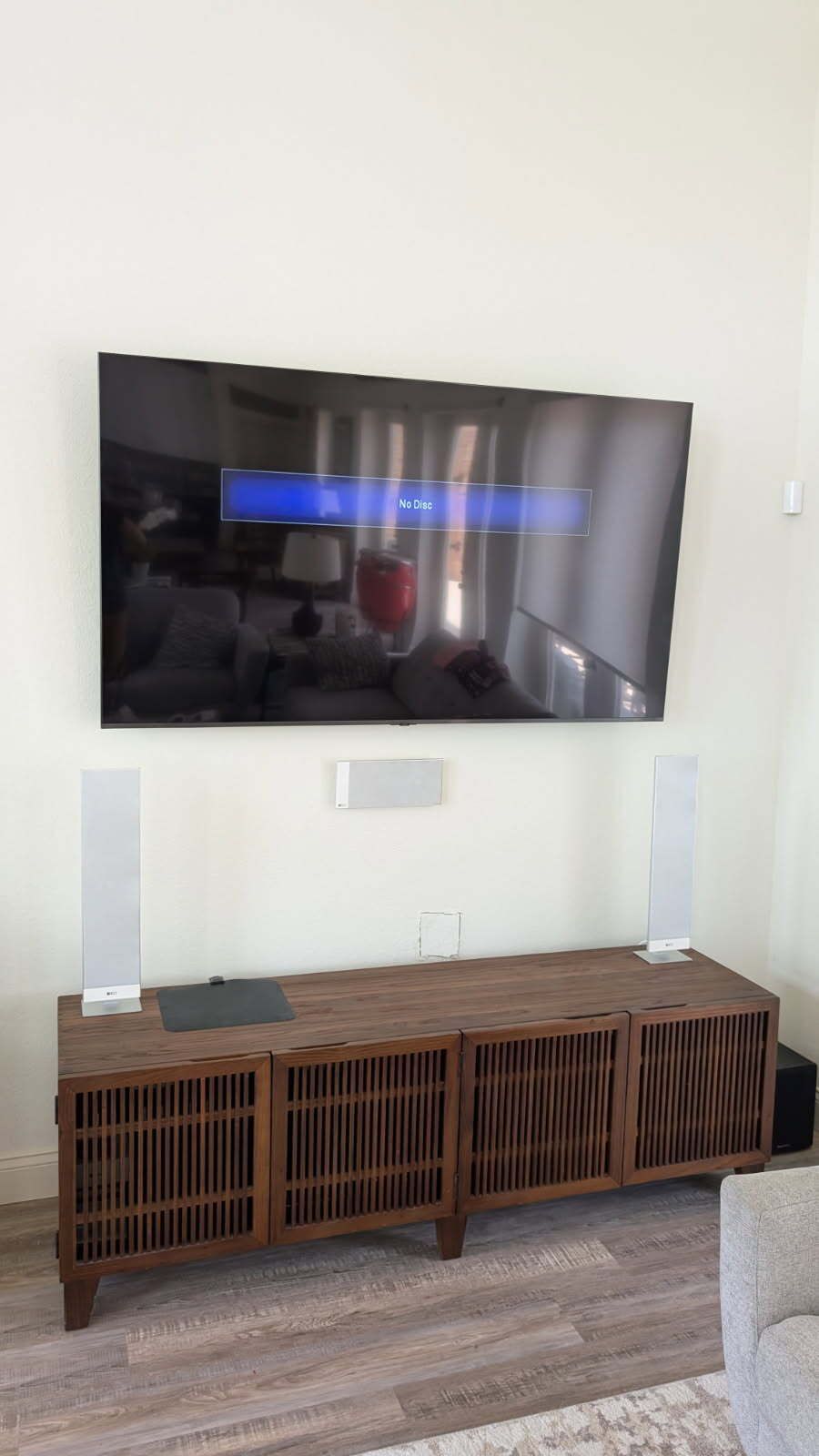 A living room with a flat screen tv mounted on the wall above a wooden entertainment center.