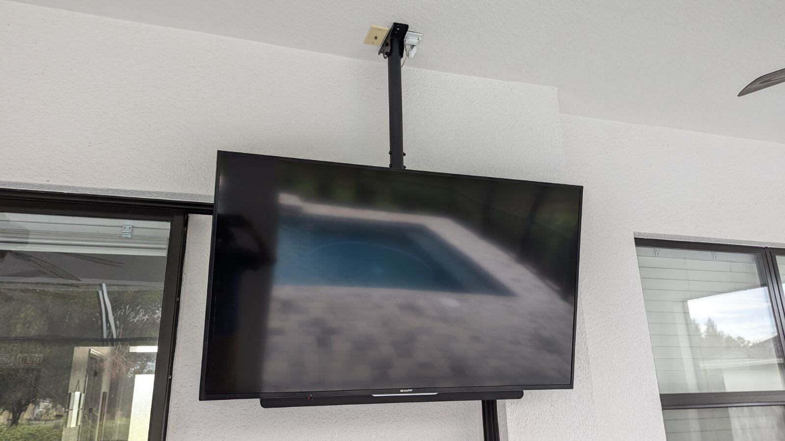 A flat screen tv is hanging from the ceiling in a room.