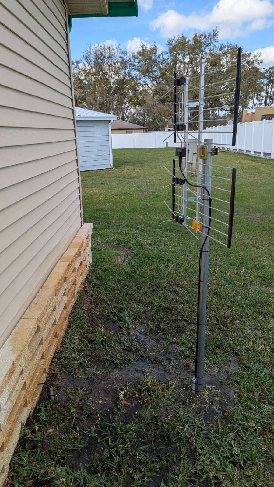 An antenna is sitting in the grass next to a house.